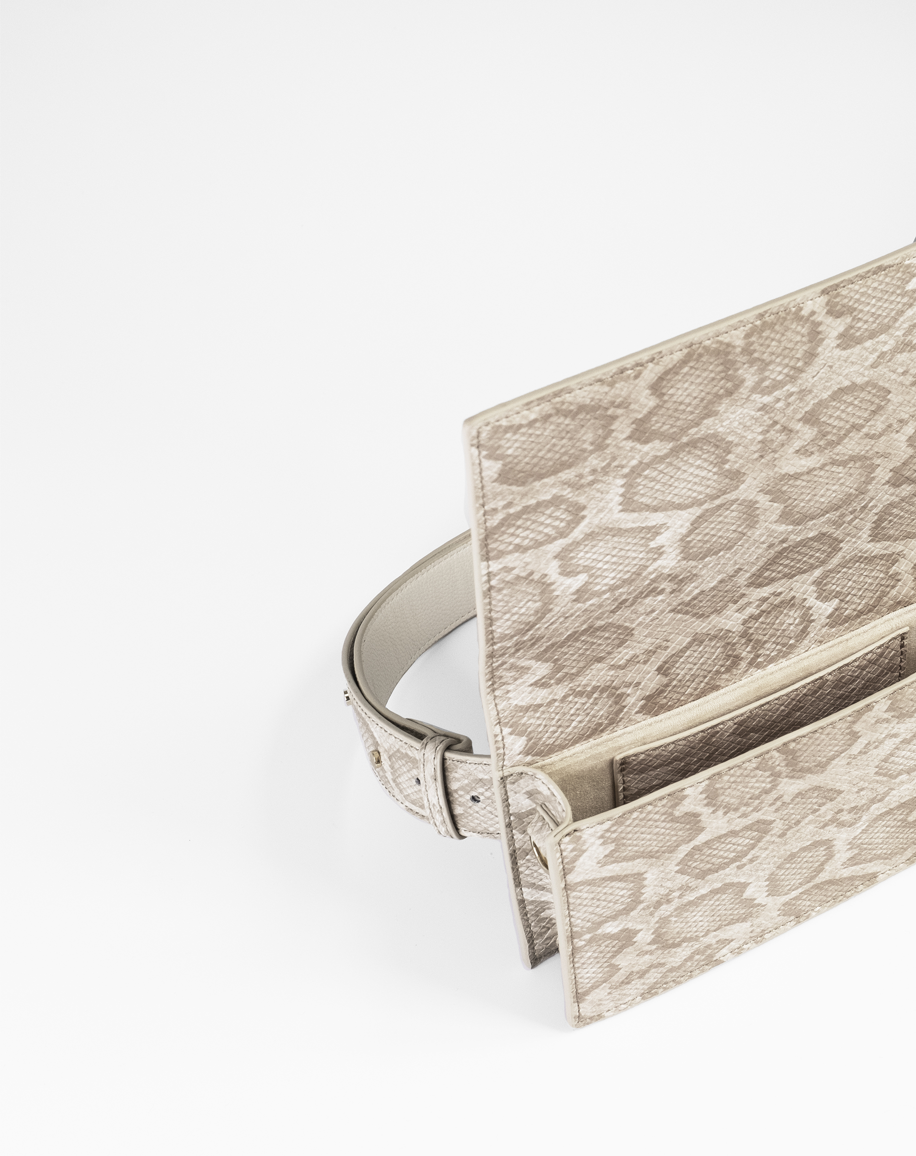 Borsa con motivo a pelle di serpente, aperta. Colore beige, con cintura. L'interno è visibile.