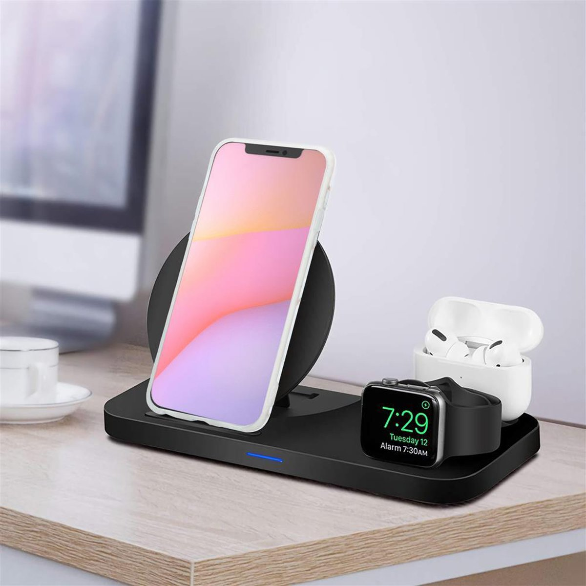 Una stazione di ricarica wireless con telefono, auricolari e smartwatch. Posizionata su una scrivania di legno.