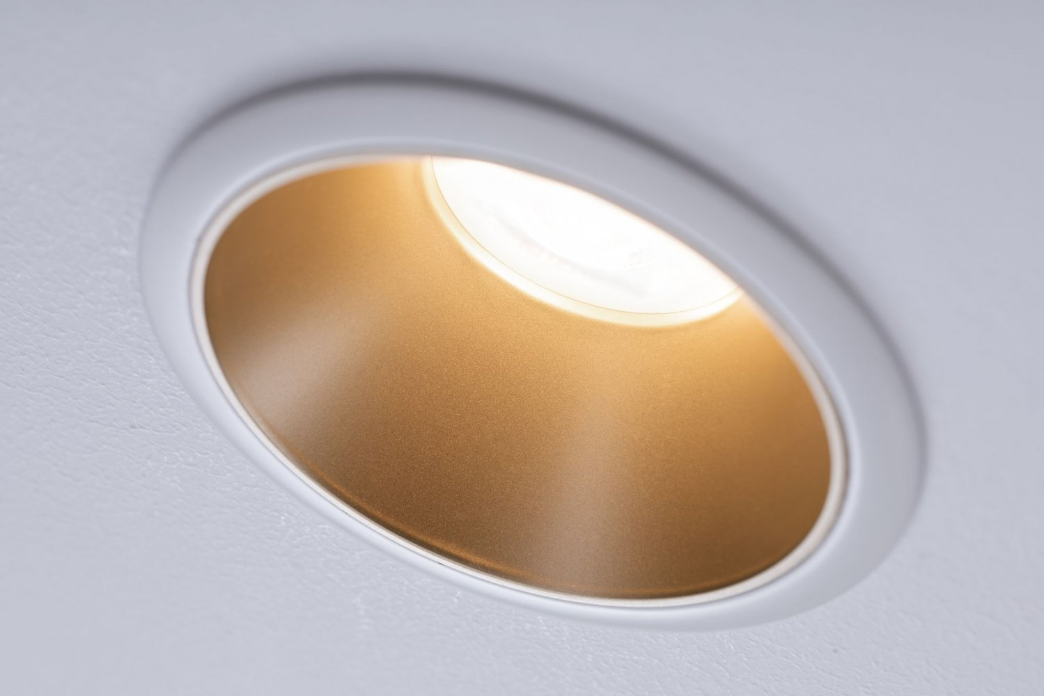 Primo piano di un faretto da incasso, che illumina l'interno con un bagliore caldo.