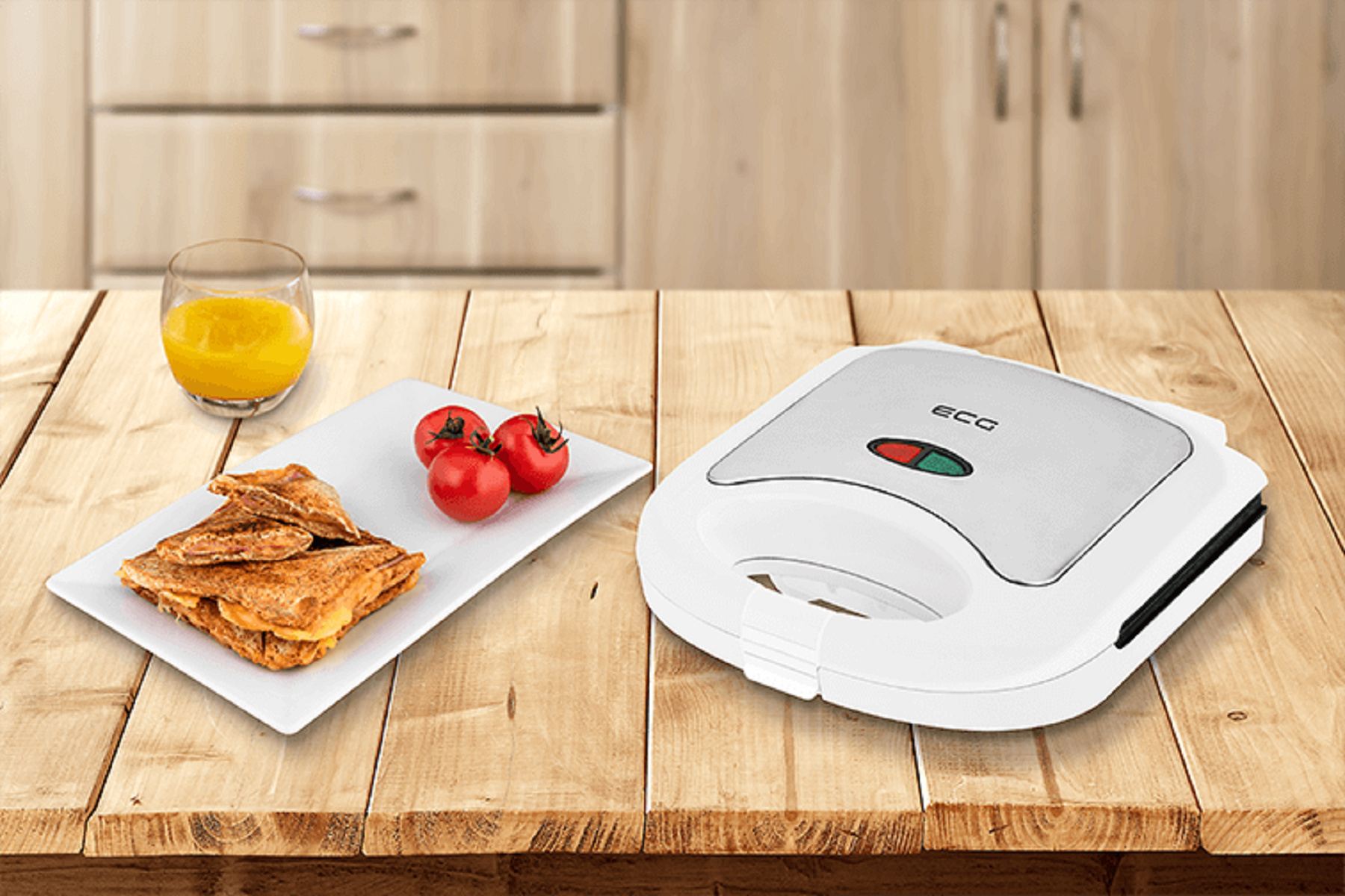 Sandwichmaker mit Sandwiches, Orangensaft und Tomaten auf einem Holztisch.