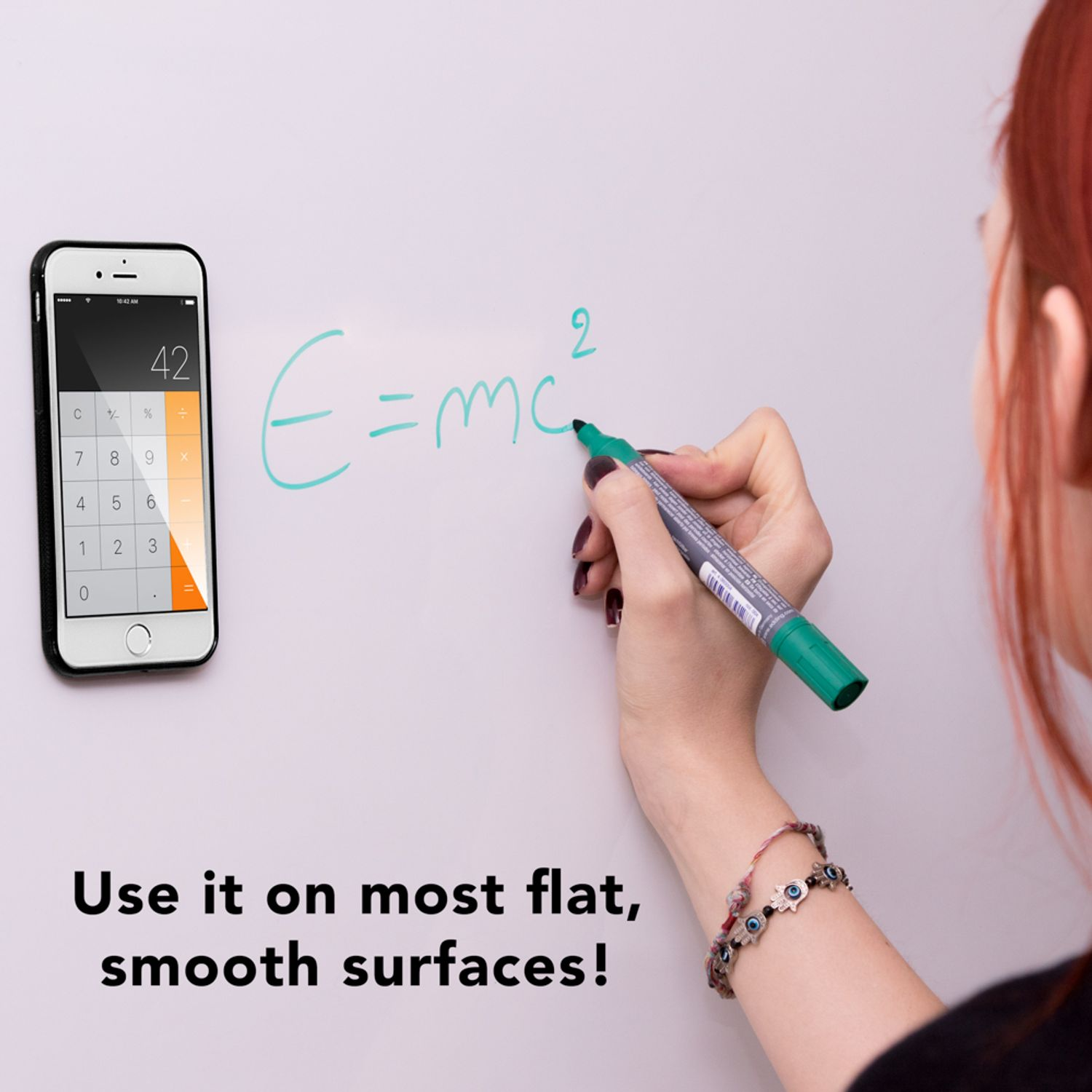Eine Frau schreibt E=mc² auf eine weiße Oberfläche. Ein Telefon zeigt einen Rechner. Text: Auf den meisten flachen, glatten Oberflächen!