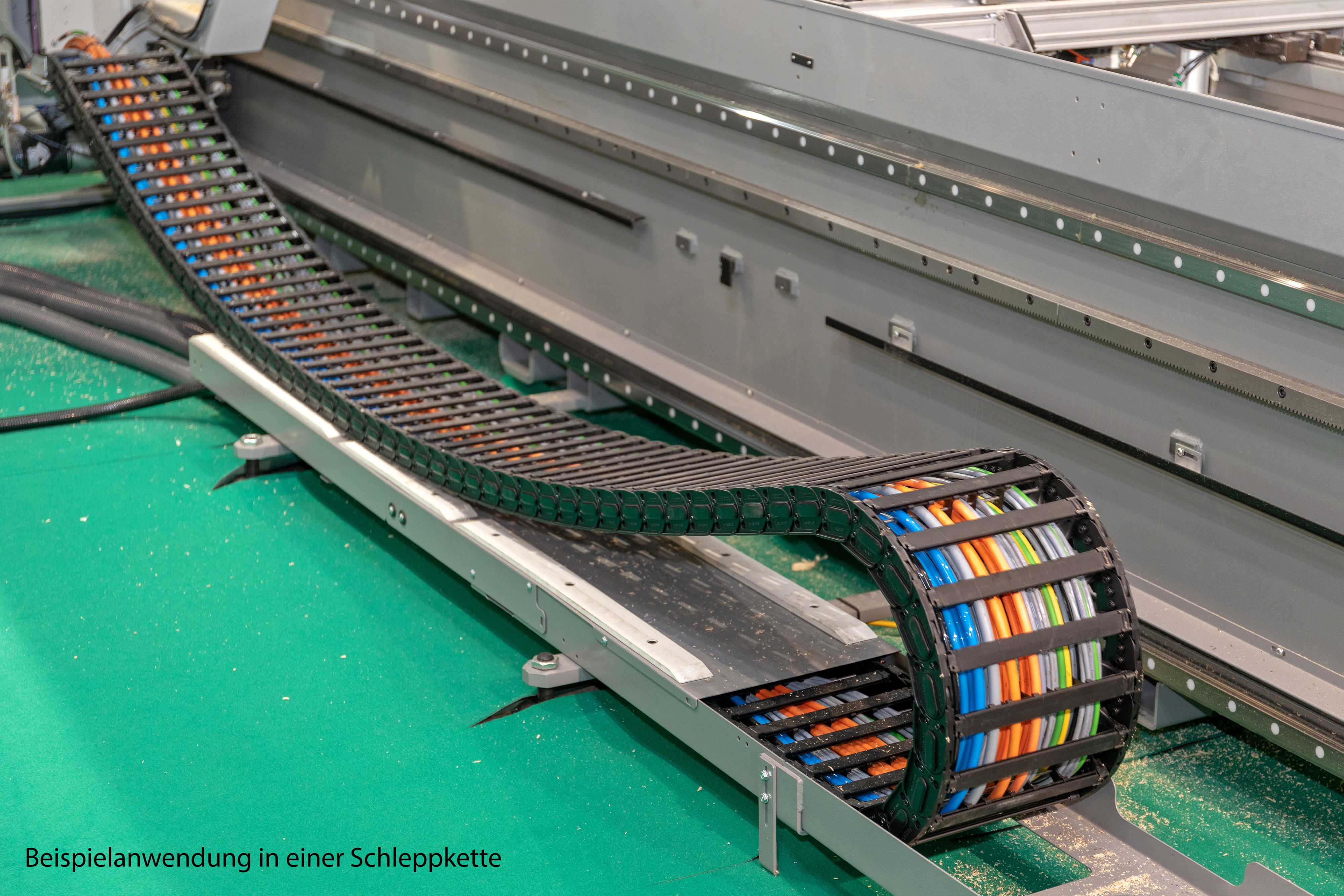 System prowadzenia kabli z wielokolorowymi kablami w środku, używany w maszynie.