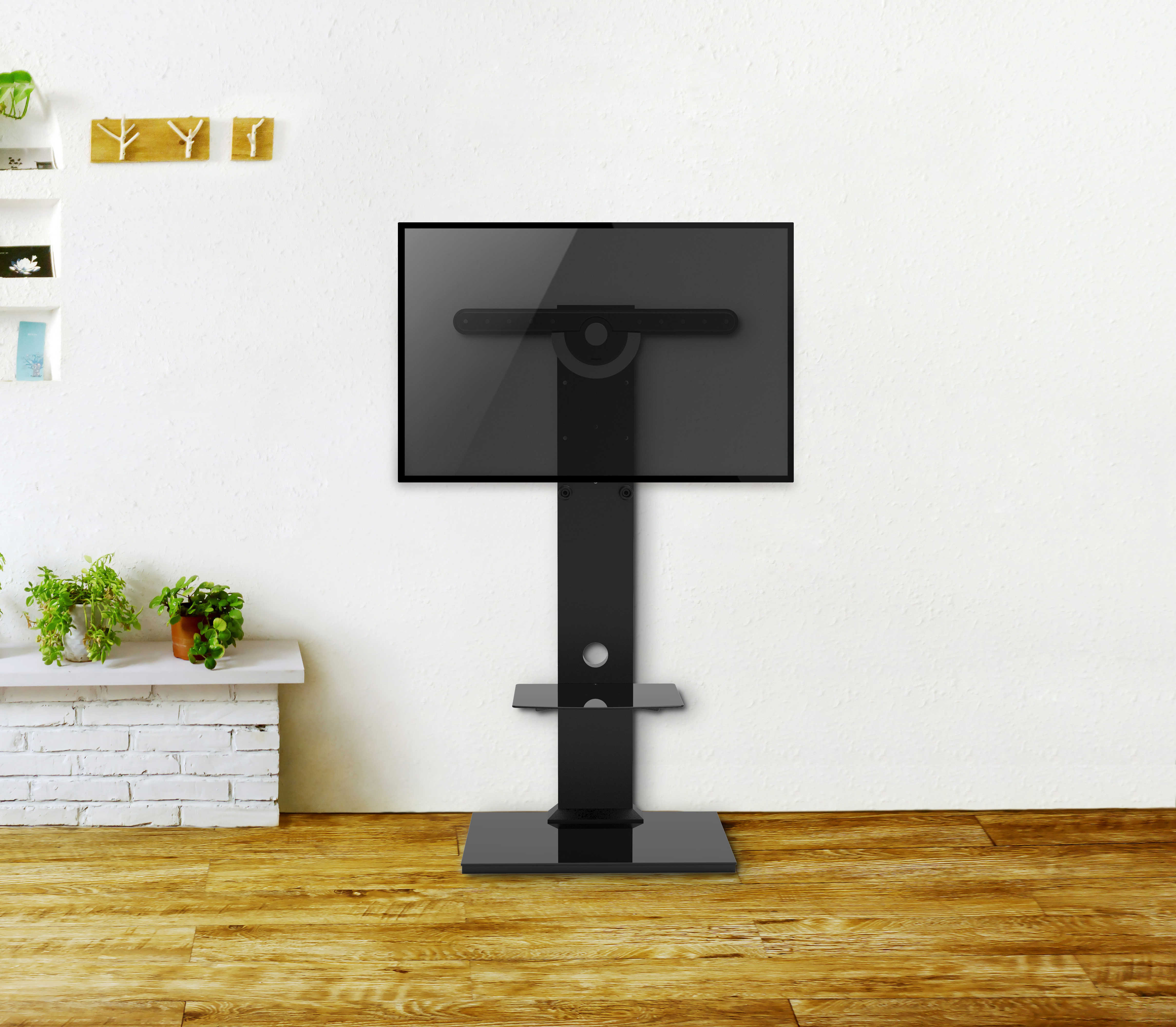 Schwarzer TV-Ständer mit montiertem Fernseher vor weißer Wand.