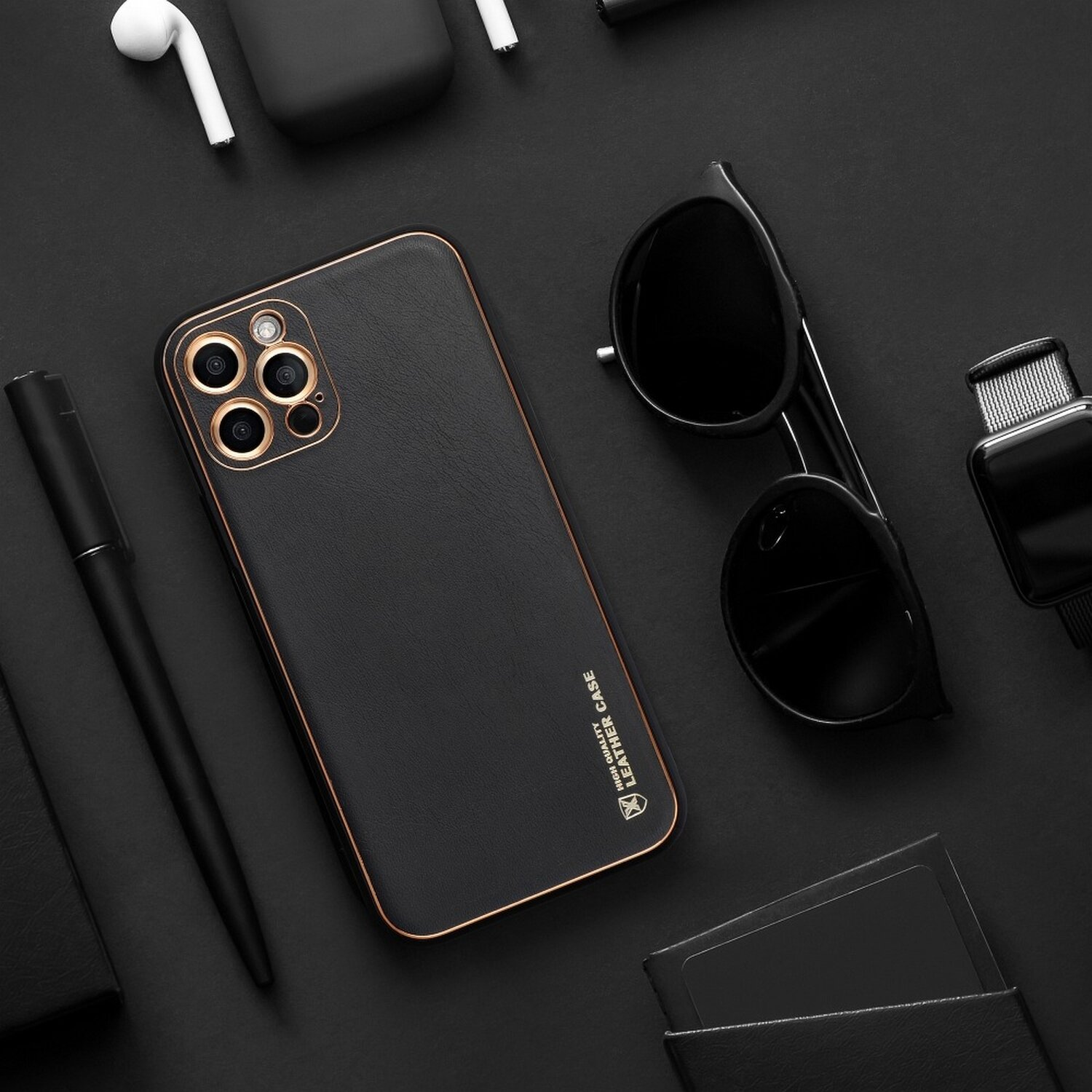 Schwarze Leder-Handyhülle mit Handy, Sonnenbrille, Stift und Zubehör auf schwarzem Grund.