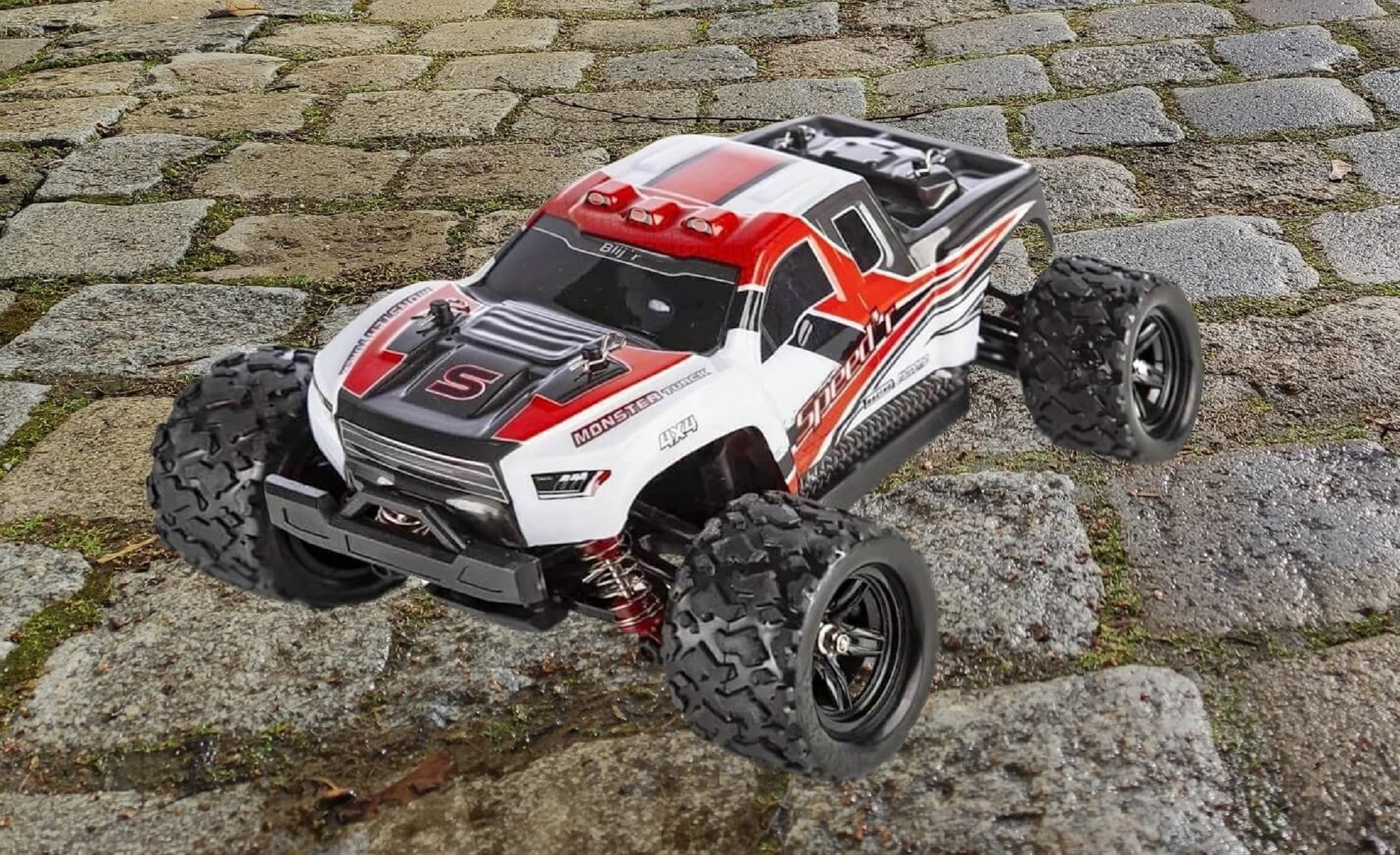 Roter, weißer und schwarzer Spielzeug-LKW auf einer Steinoberfläche. Er hat große Reifen und 4x4-Label.