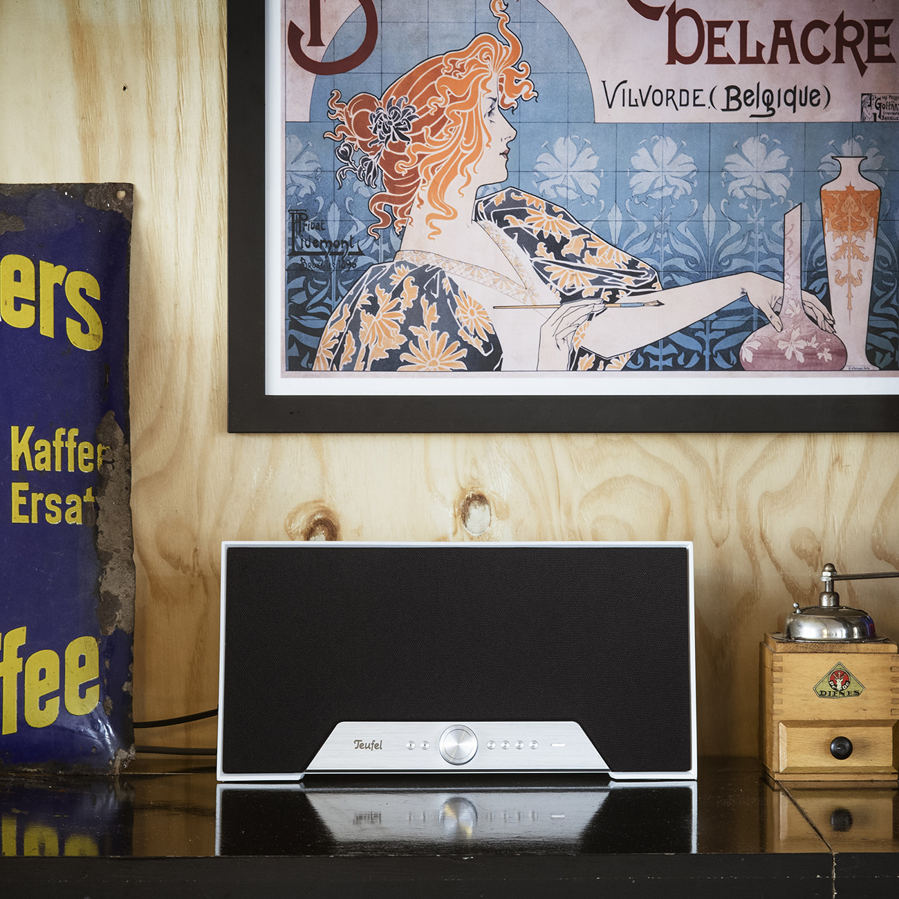 Een stereosysteem op een zwart schap, met een vintage poster en decoratie.
