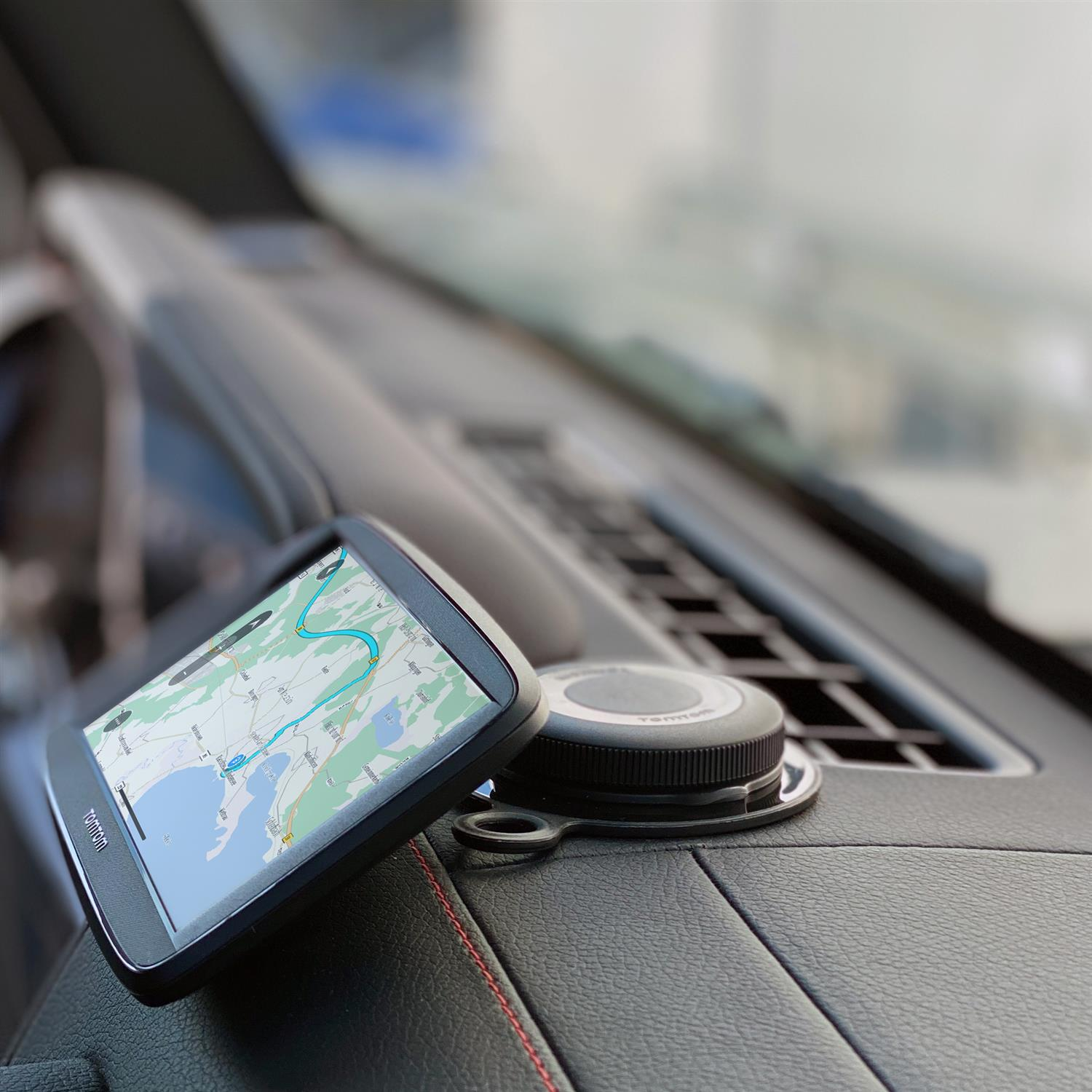 GPS-Gerät auf dem Armaturenbrett eines Autos. Karte auf dem Bildschirm, TomTom-Logo sichtbar.