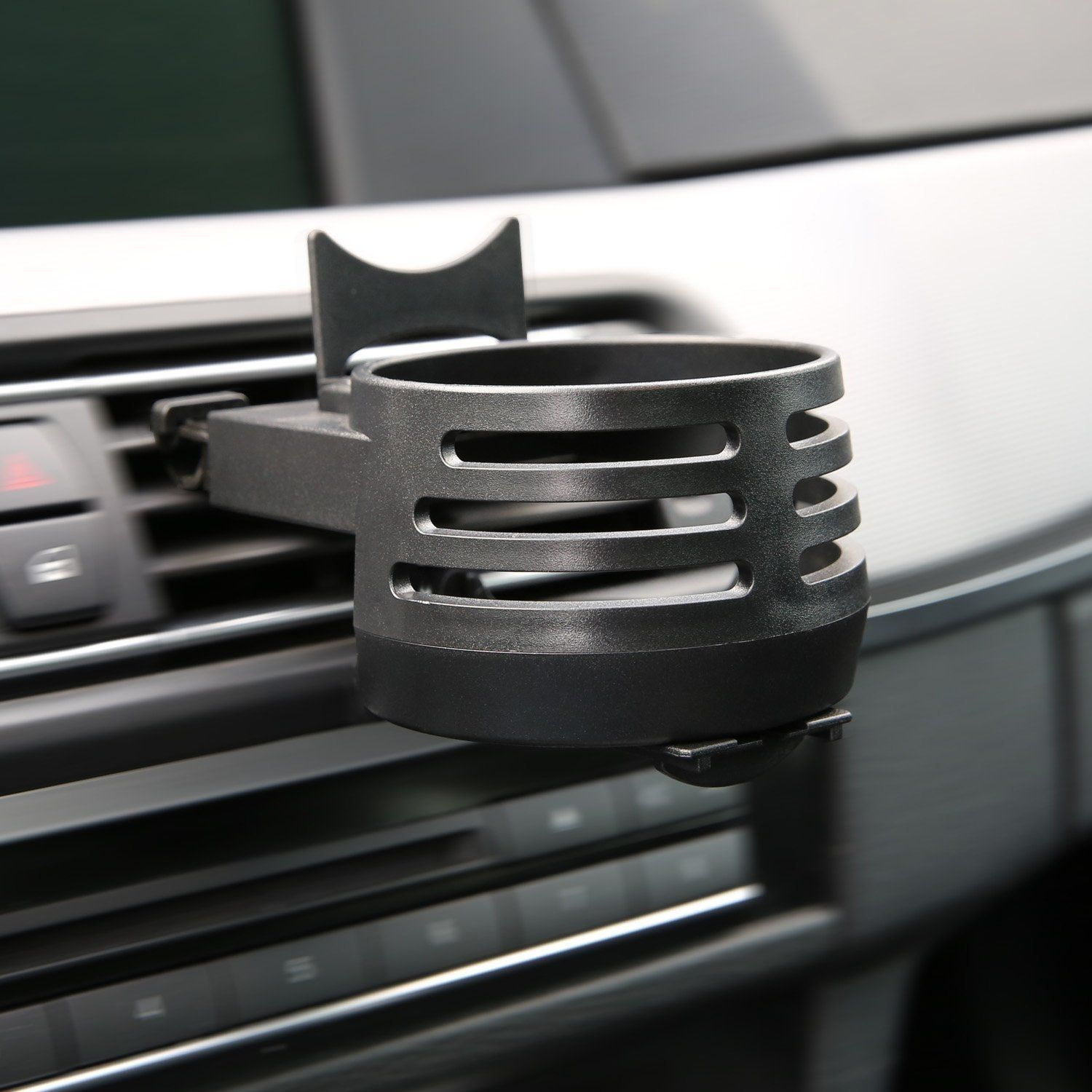 Ein schwarzer Getränkehalter für Autos, der in einem Auto mit anderen Bedienelementen installiert ist.