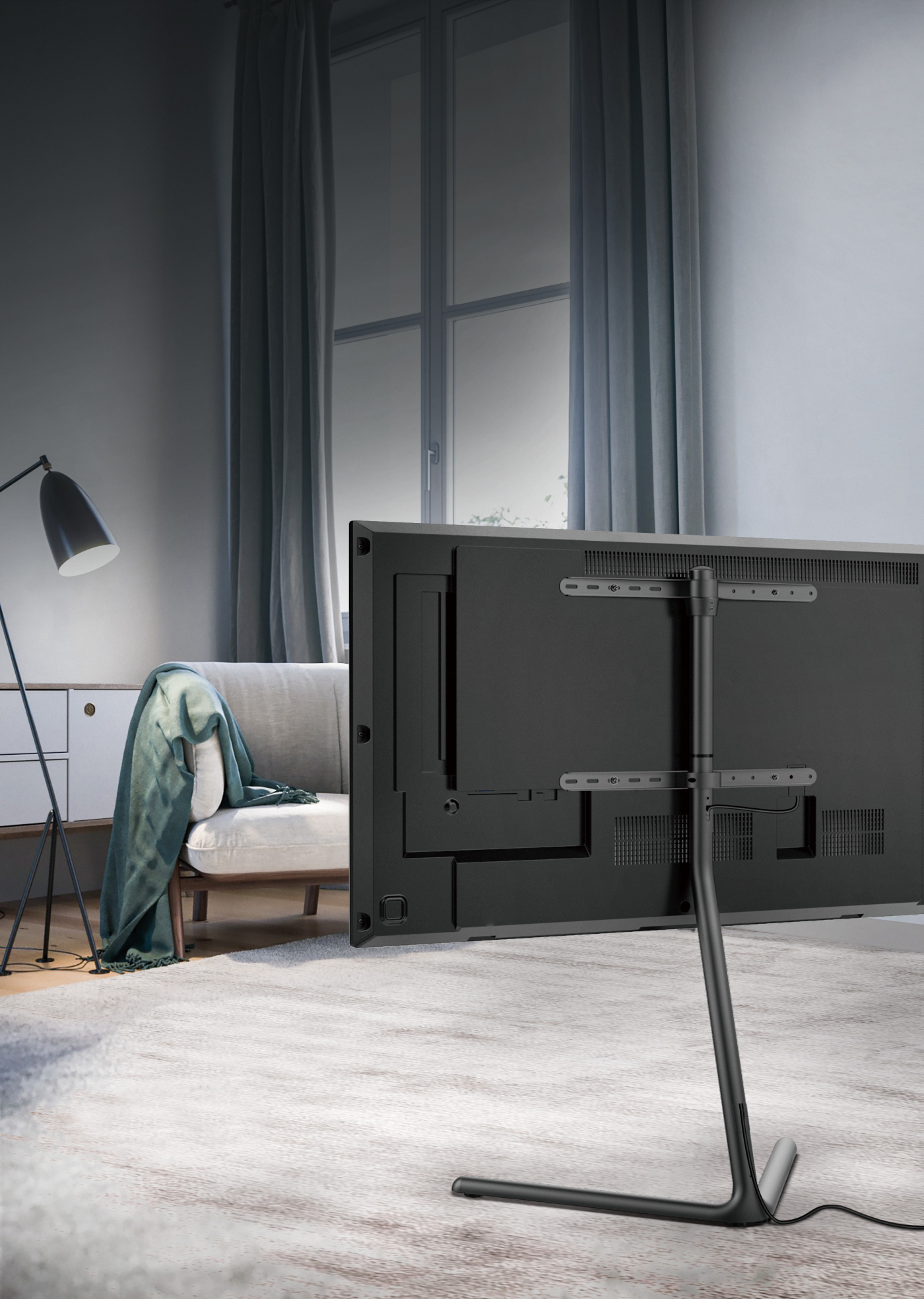 Ein schwarzer Fernseher auf einem Ständer in einem Wohnzimmer. Fenster und eine Lampe sind sichtbar.