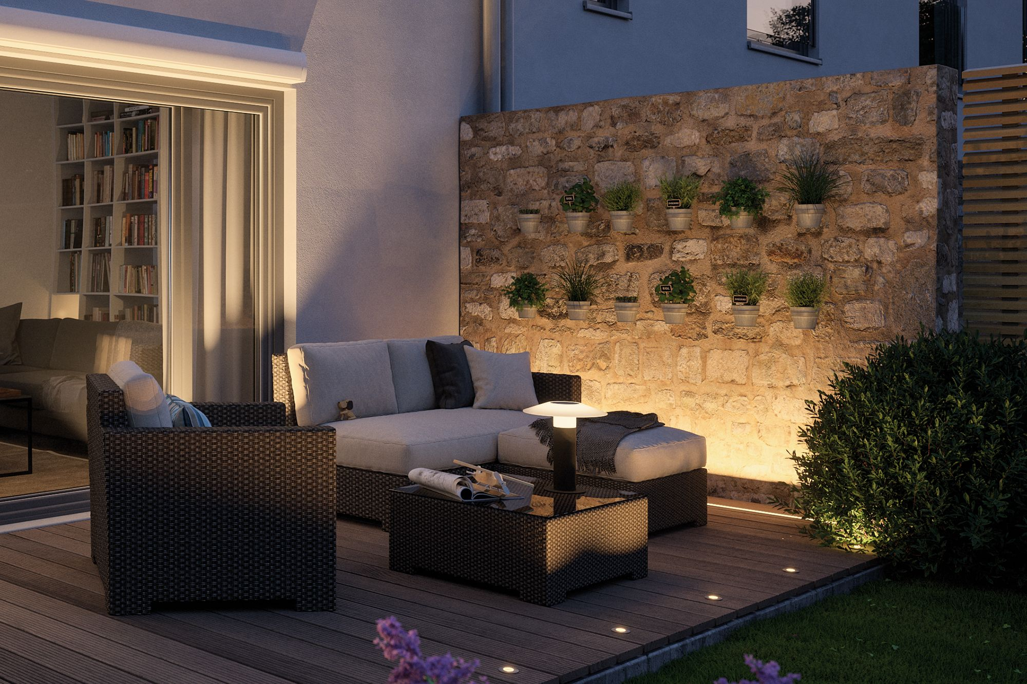 Terrasse mit Sitzgelegenheiten, Steinmauer mit Pflanzen und beleuchtetem Weg.