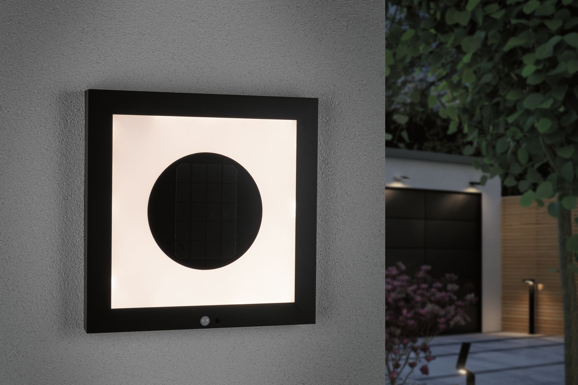 Schwarze quadratische Leuchte an einer Wand. Ein weißes Quadrat in der Mitte mit einem schwarzen Kreis.