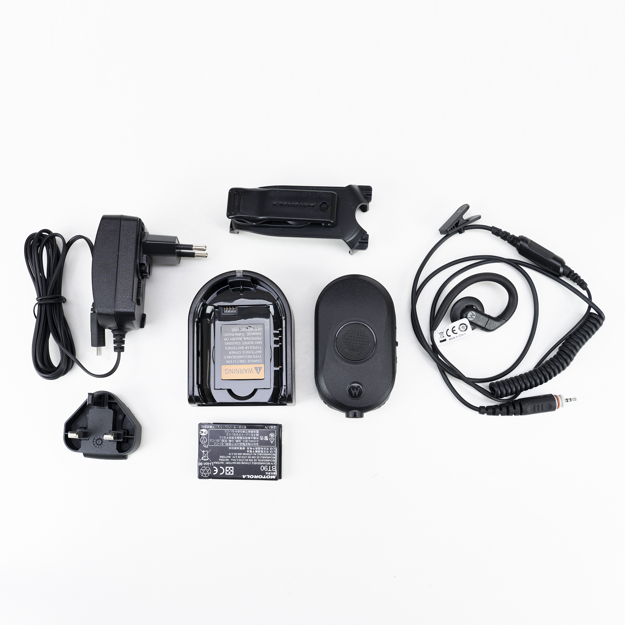 Varias partes de un juego de radio Motorola, que incluyen cargador, batería y auriculares, sobre una superficie blanca.
