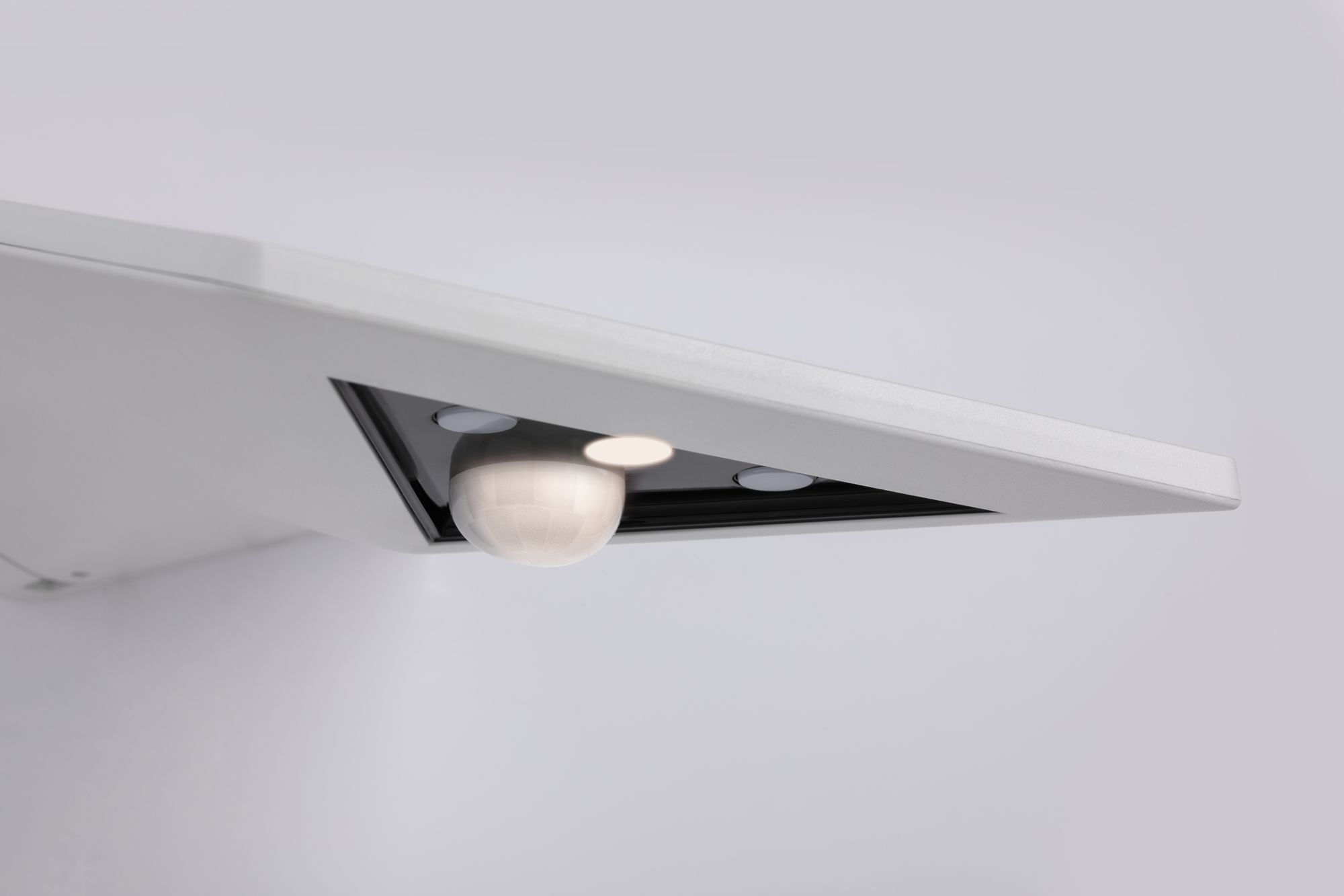 Vista inferiore di un apparecchio di illuminazione bianco, con un sensore di movimento.