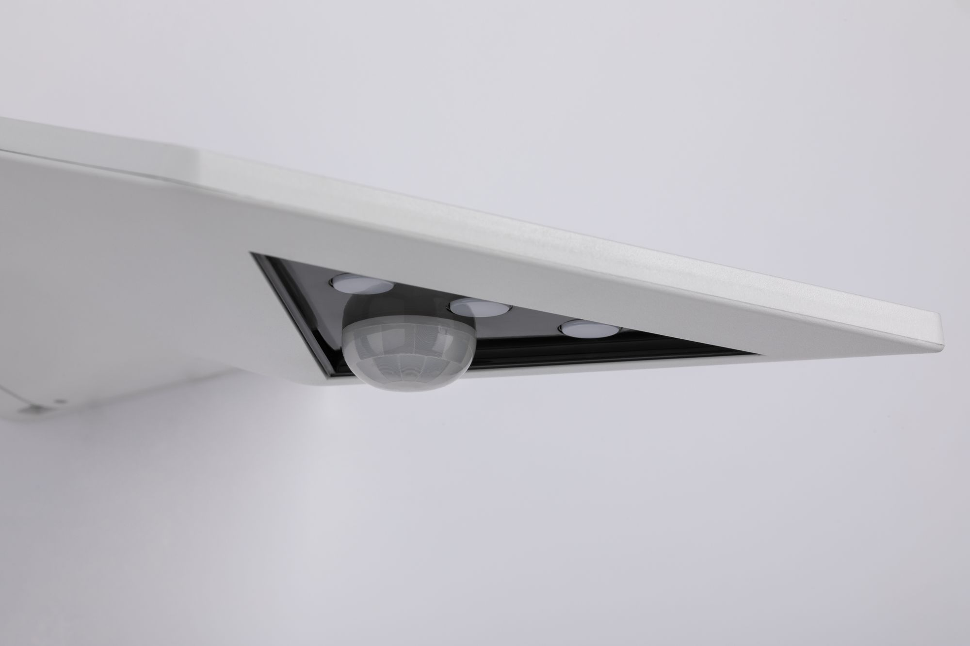 Una luce rettangolare bianca con un sensore di movimento. La luce ha un pannello sensore rettangolare scuro.