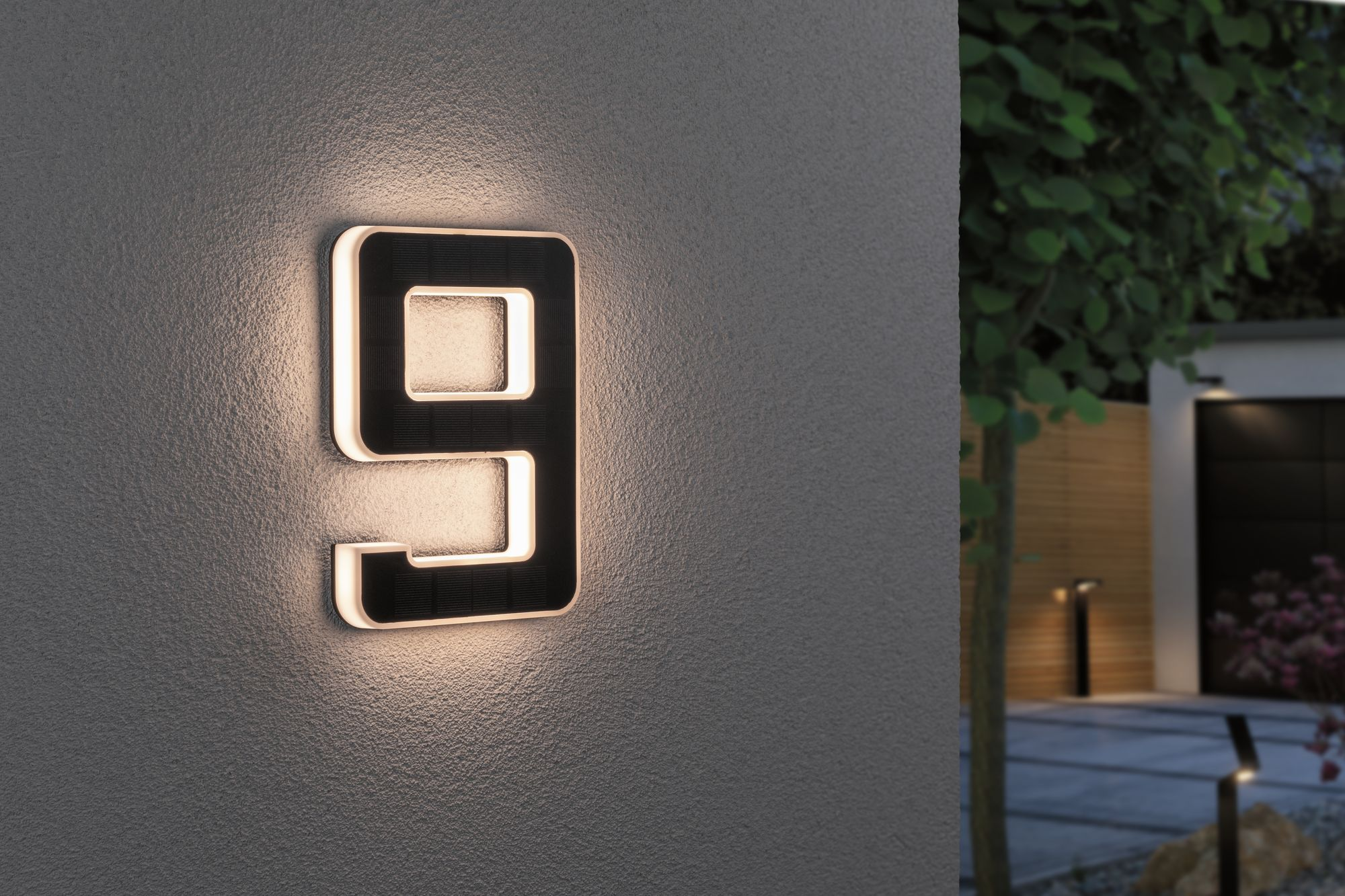 Podświetlony numer domu dziewięć na teksturowanej ścianie.