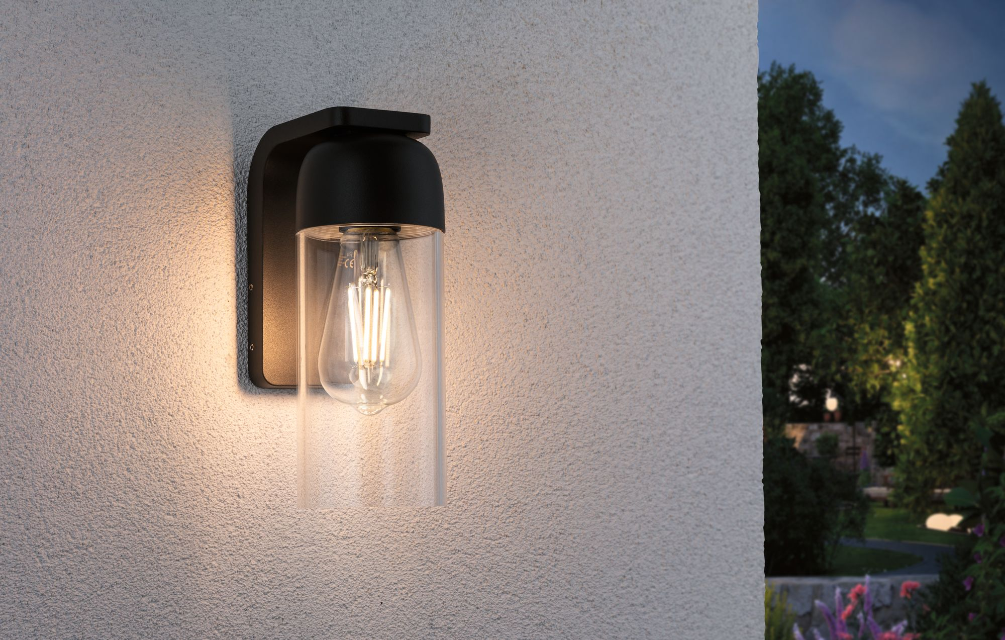 Zewnętrzna lampa ścienna z przezroczystym szkłem i widoczną żarówką.