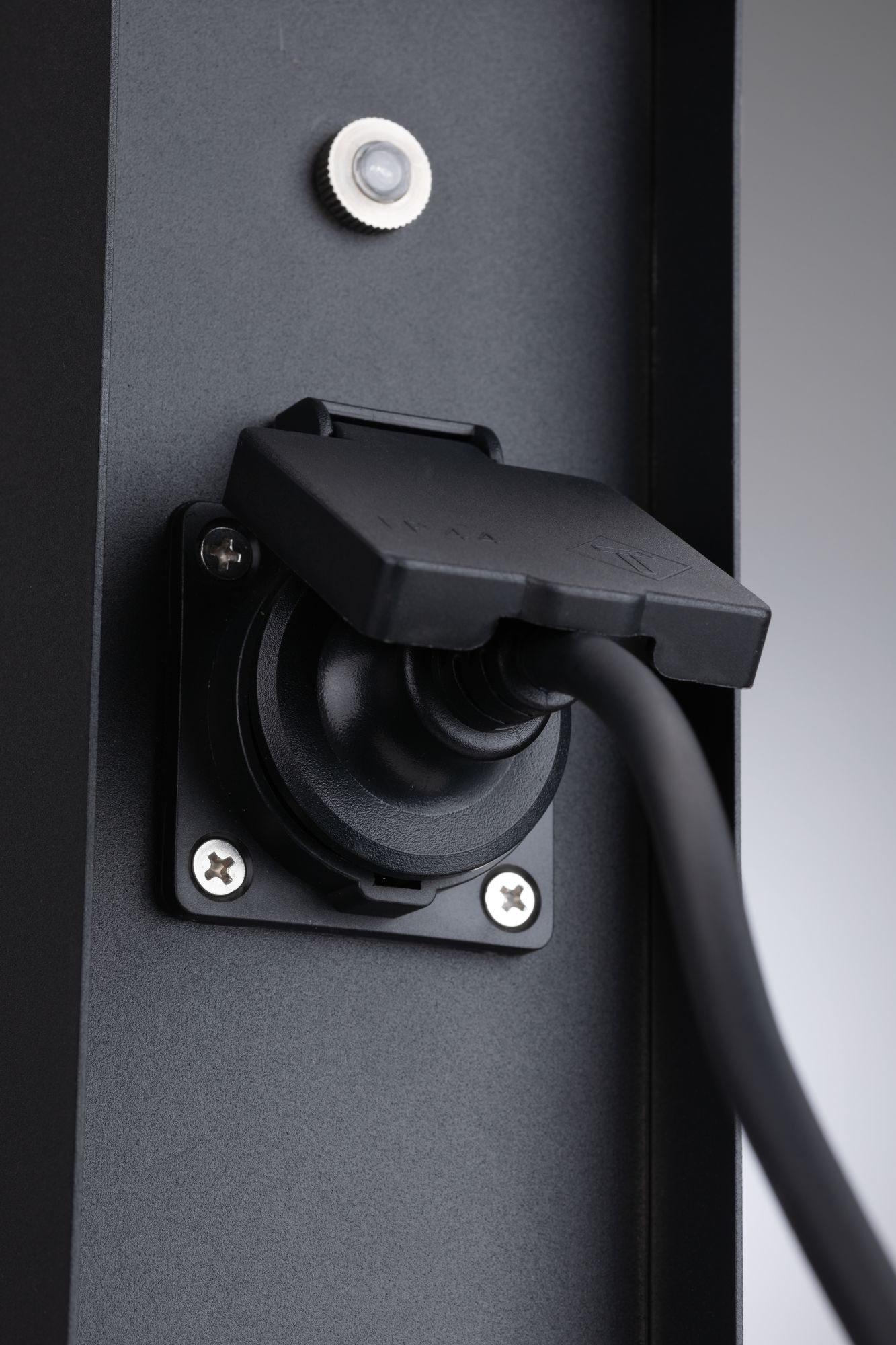 Czarne gniazdo z osłoną. Czarny kabel jest podłączony do gniazda.