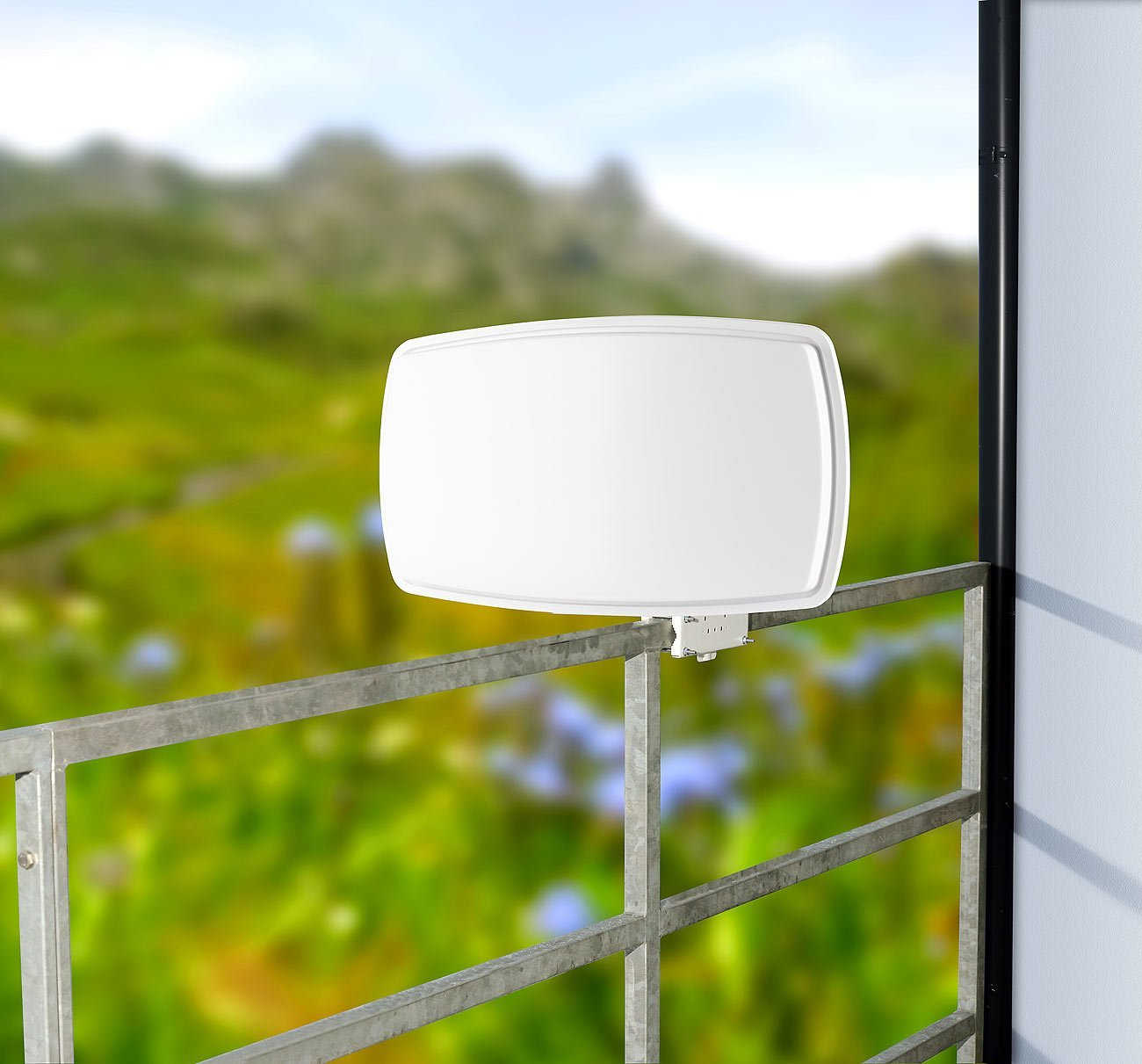 Weisse Antenne an einem Geländer mit grüner Landschaft im Hintergrund.