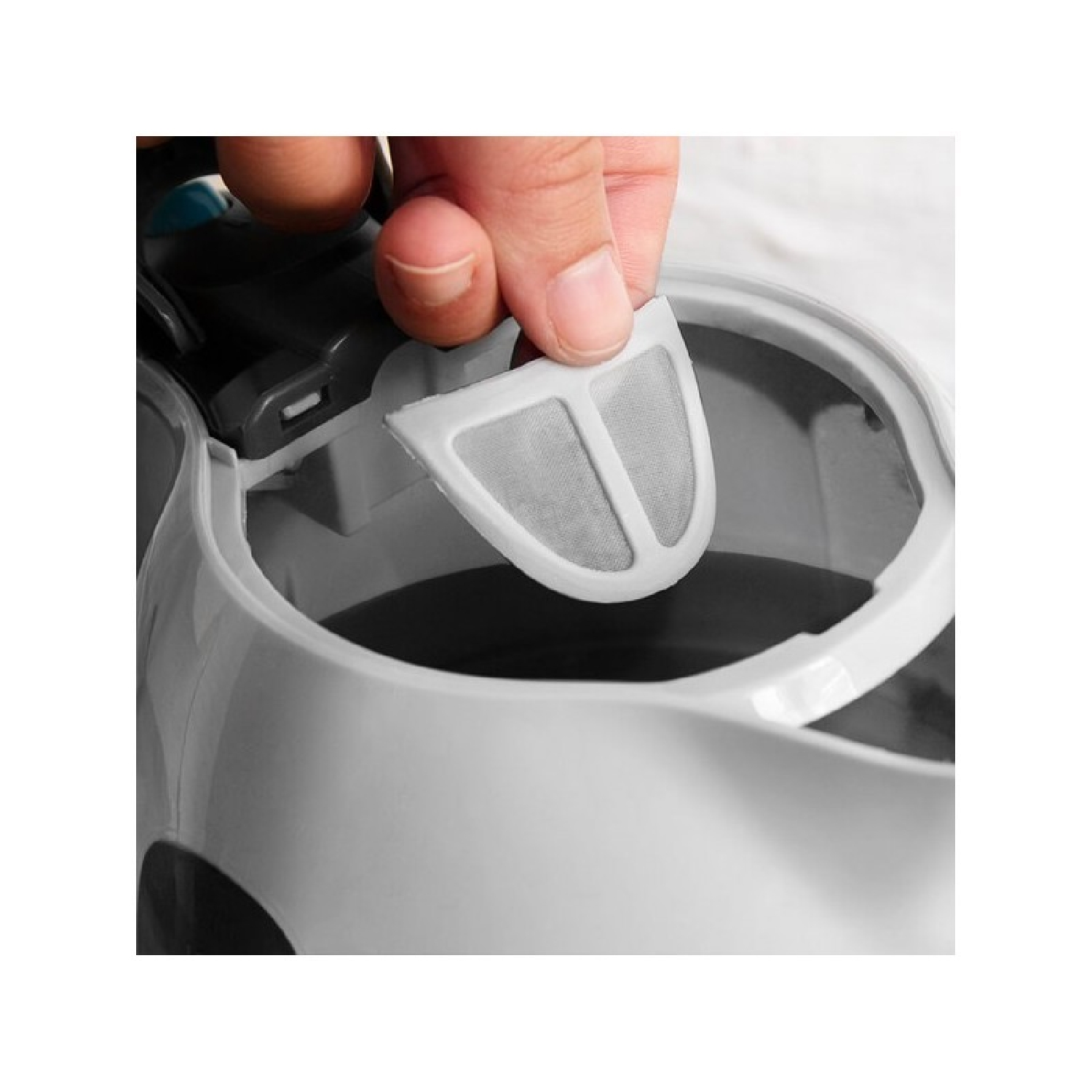 Een hand verwijdert een filter uit een witte waterkoker.