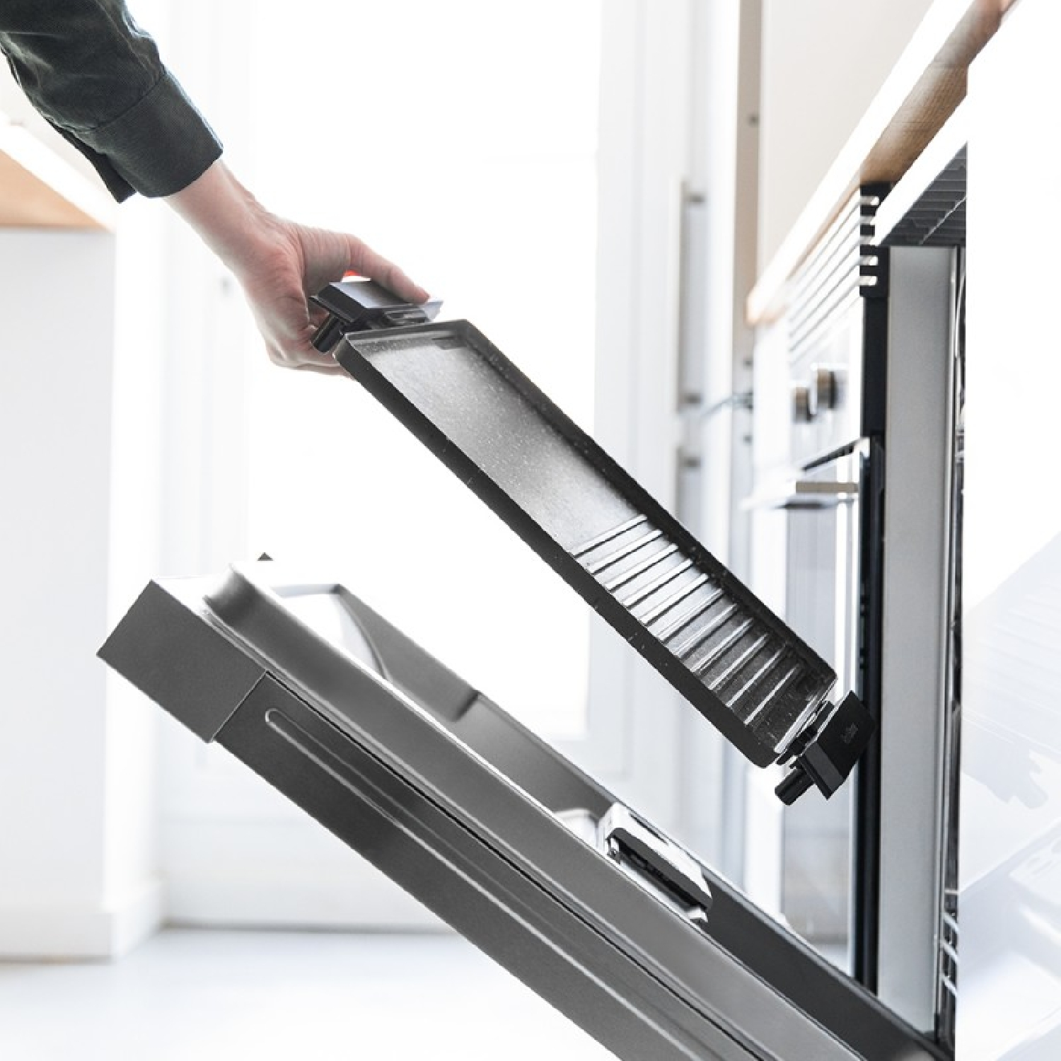 Una persona rimuove una griglia dal forno. Il forno è aperto. La griglia è grigio scuro.
