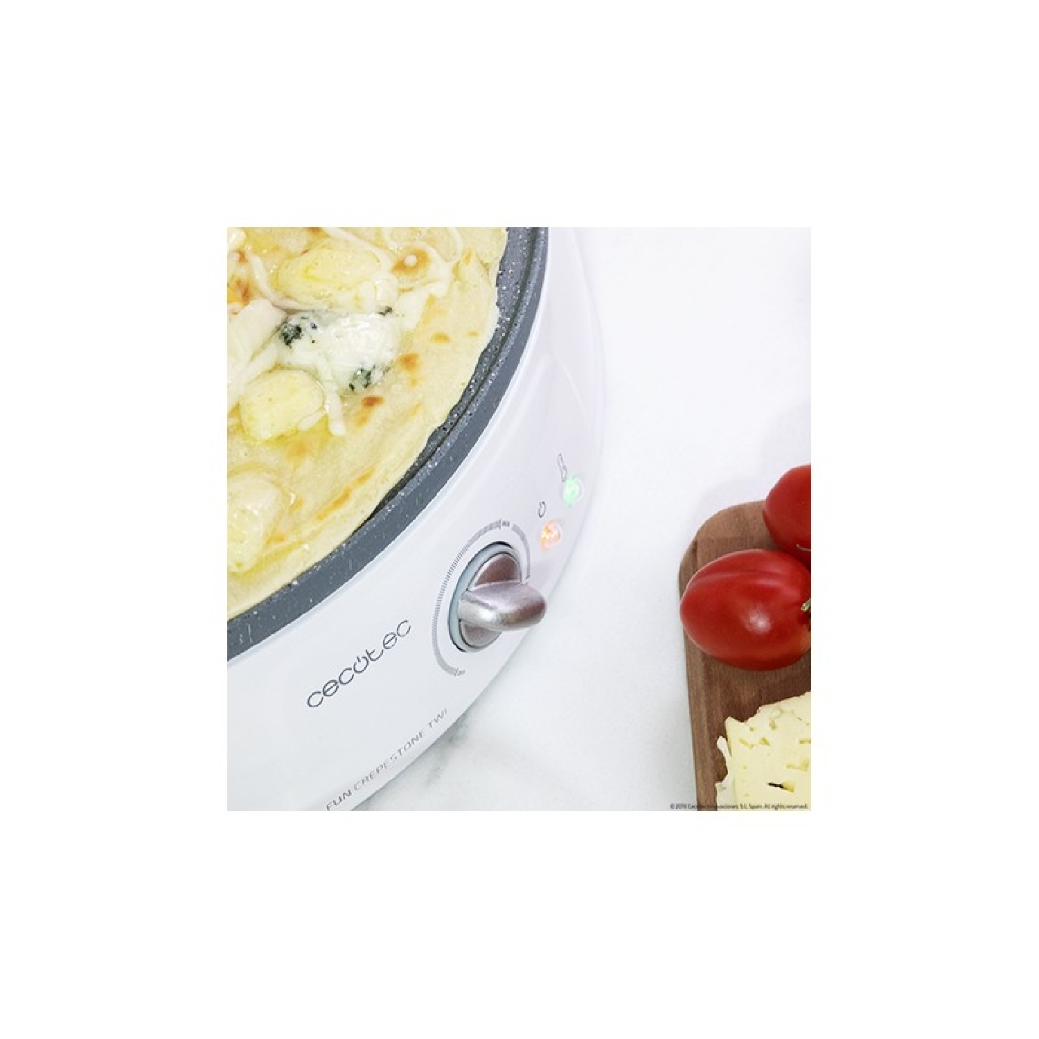 Una crepiera bianca con una piccola pizza e pomodori. Il dispositivo ha una manopola di controllo e spie.
