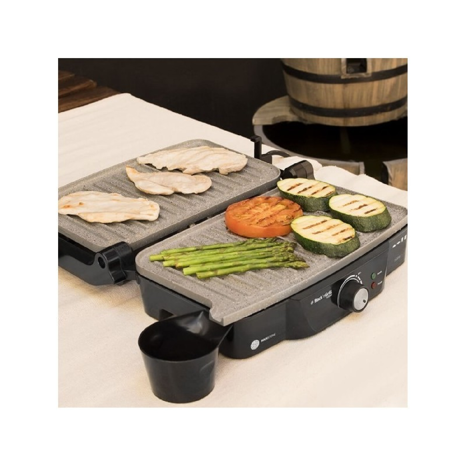 Grill z grillowanymi warzywami i kurczakiem. Grill stoi na stole z czarnym uchwytem.