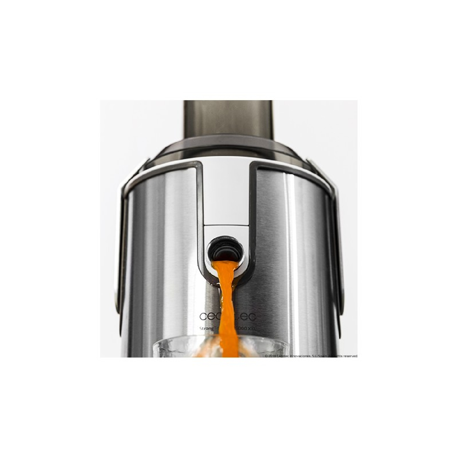 Jugo vertiéndose de una exprimidora plateada a un vaso. Líquido naranja.