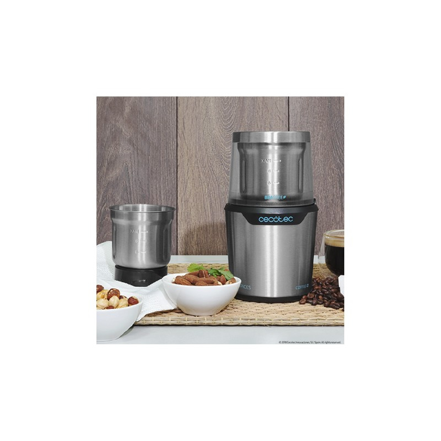 Srebrno-czarny młynek do kawy z dwoma miseczkami i składnikami w pobliżu.