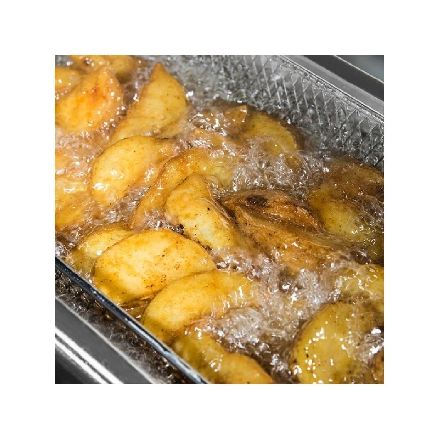 Zbliżenie na smażone kliny ziemniaczane w metalowym koszu zanurzonym w gorącym oleju.