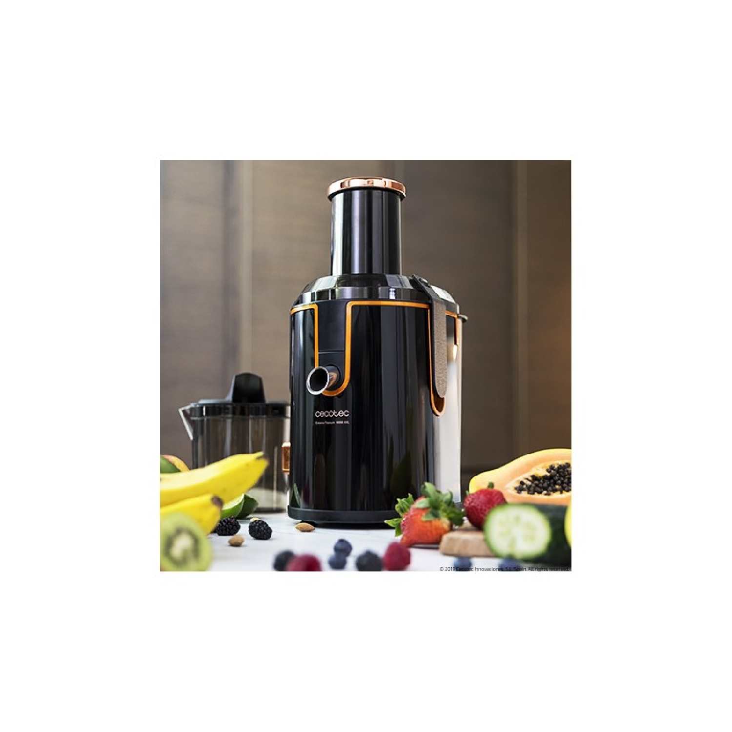 Estrattore di succo nero e oro con frutta e ingredienti su una superficie bianca. Lo sfondo è neutro.