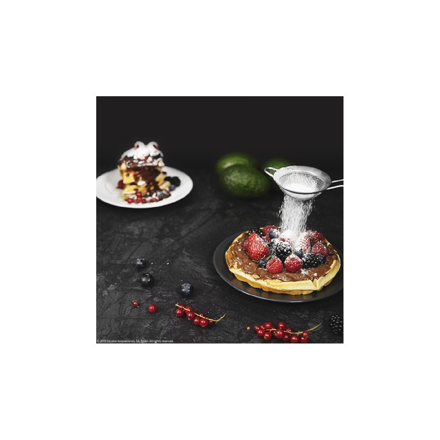 Gofry z jagodami i cukrem pudrem. Sito posypuje cukrem.