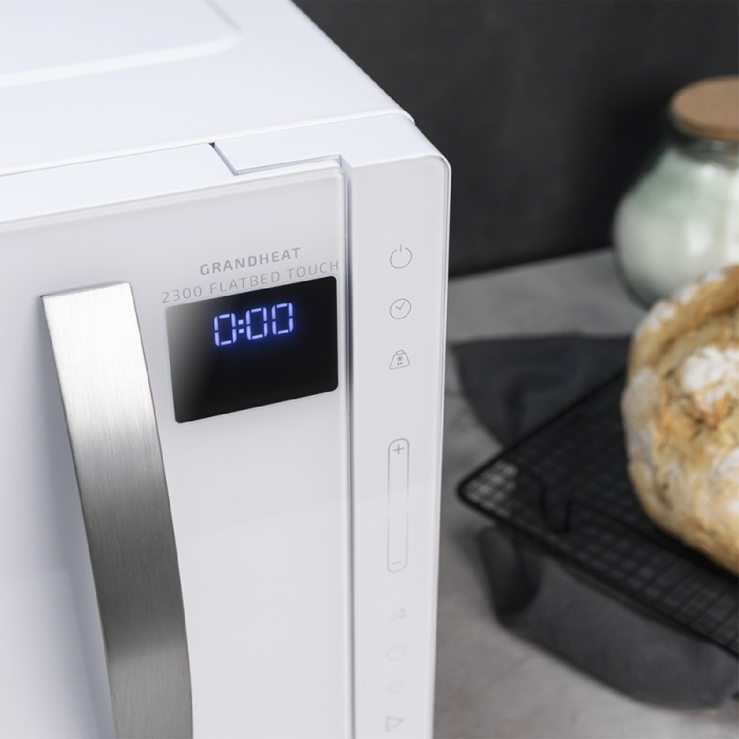 Een witte magnetron toont 0:00 op de timer. De deur is gesloten. Keukenachtergrond.