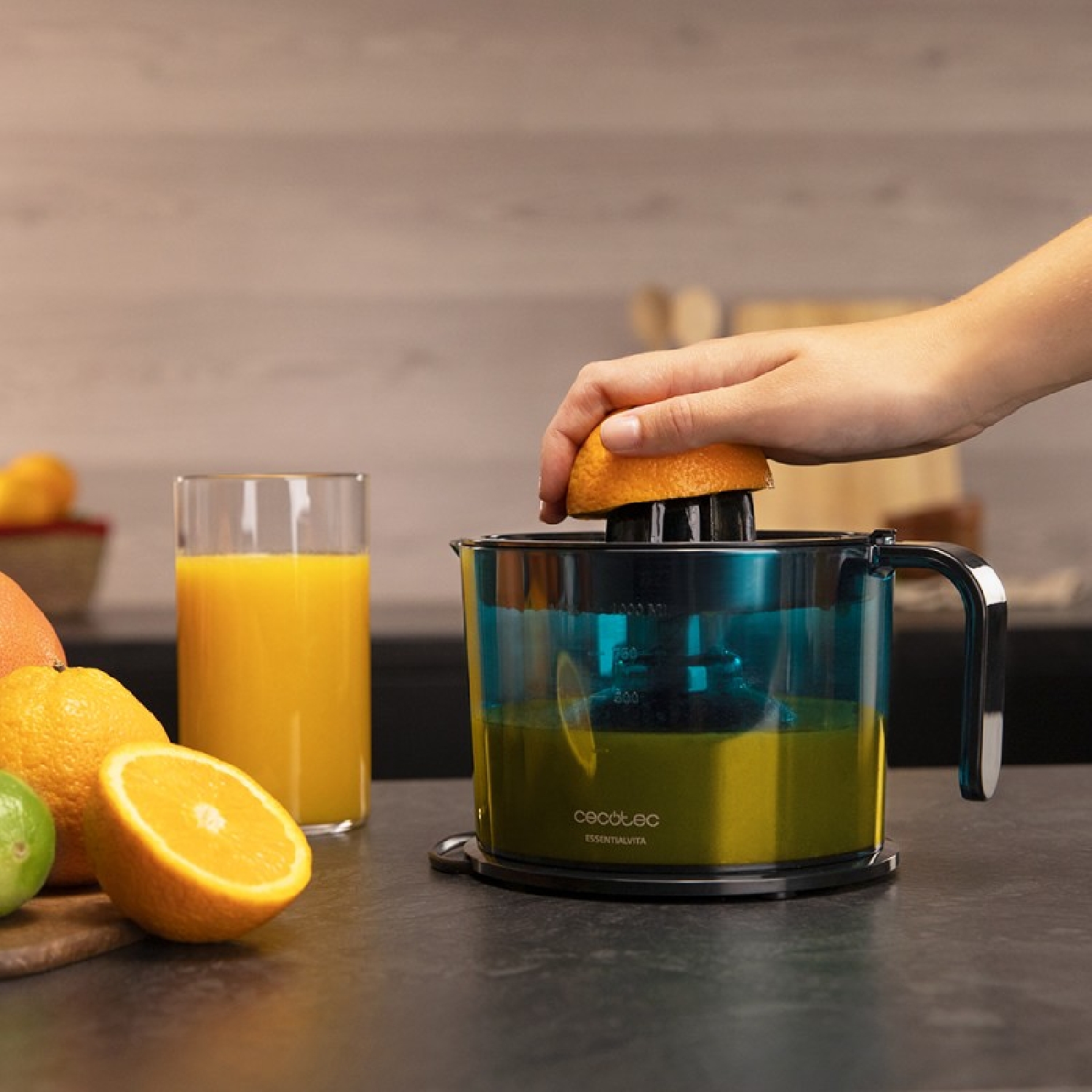 Una mano che sprema mezza arancia in uno spremiagrumi con succo d'arancia.