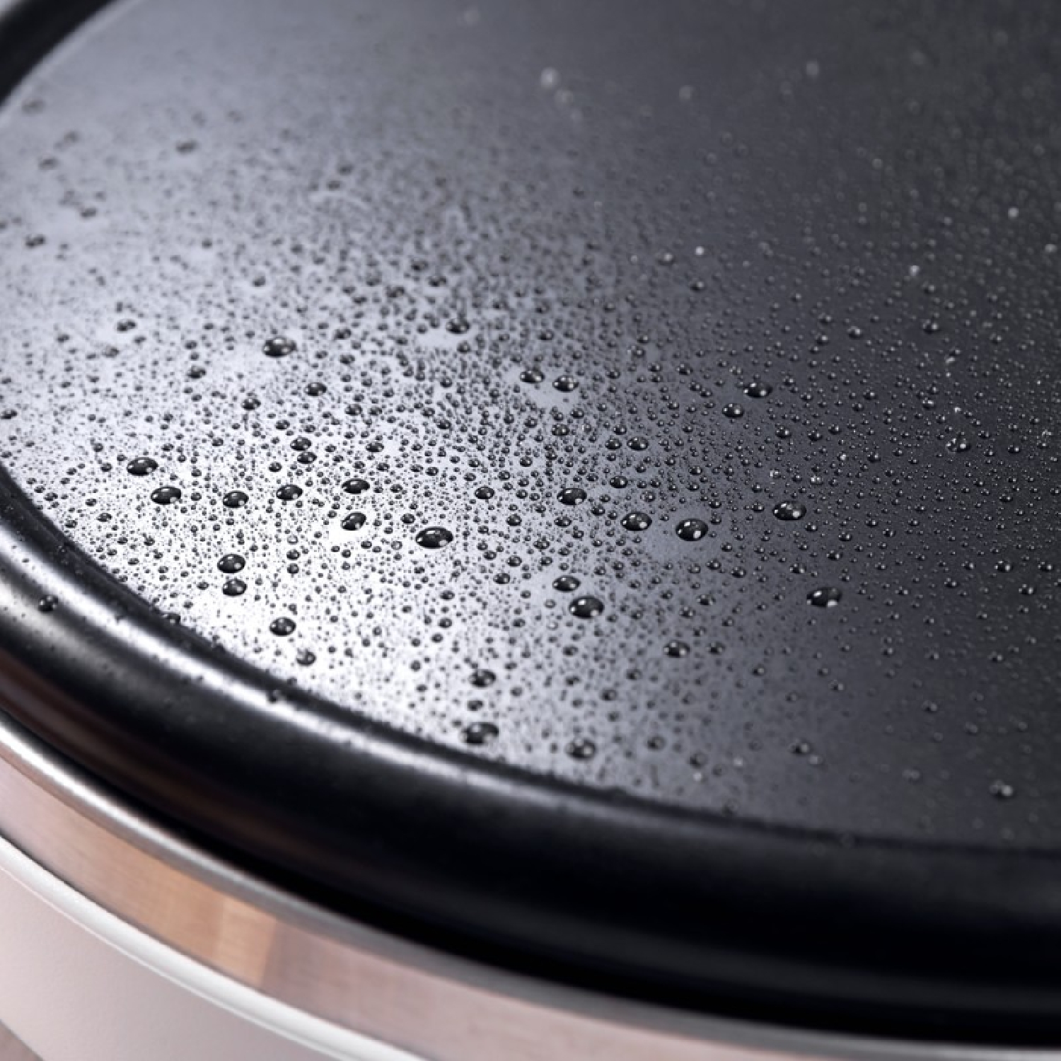 Zbliżenie czarnej powierzchni do gotowania z wieloma kroplami wody.