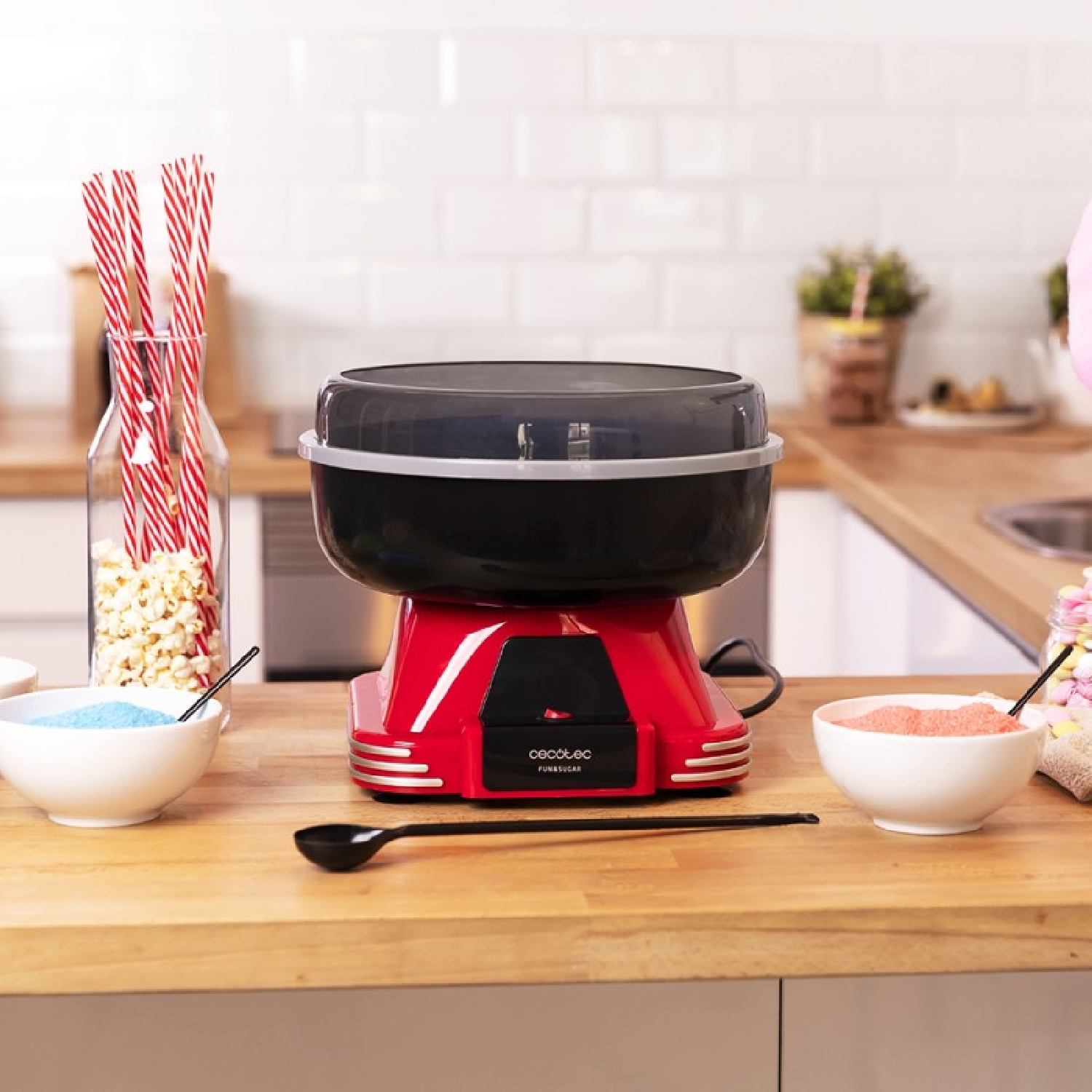 Macchina per lo zucchero filato con accessori su una superficie di legno, sfondo bianco, ambiente cucina.