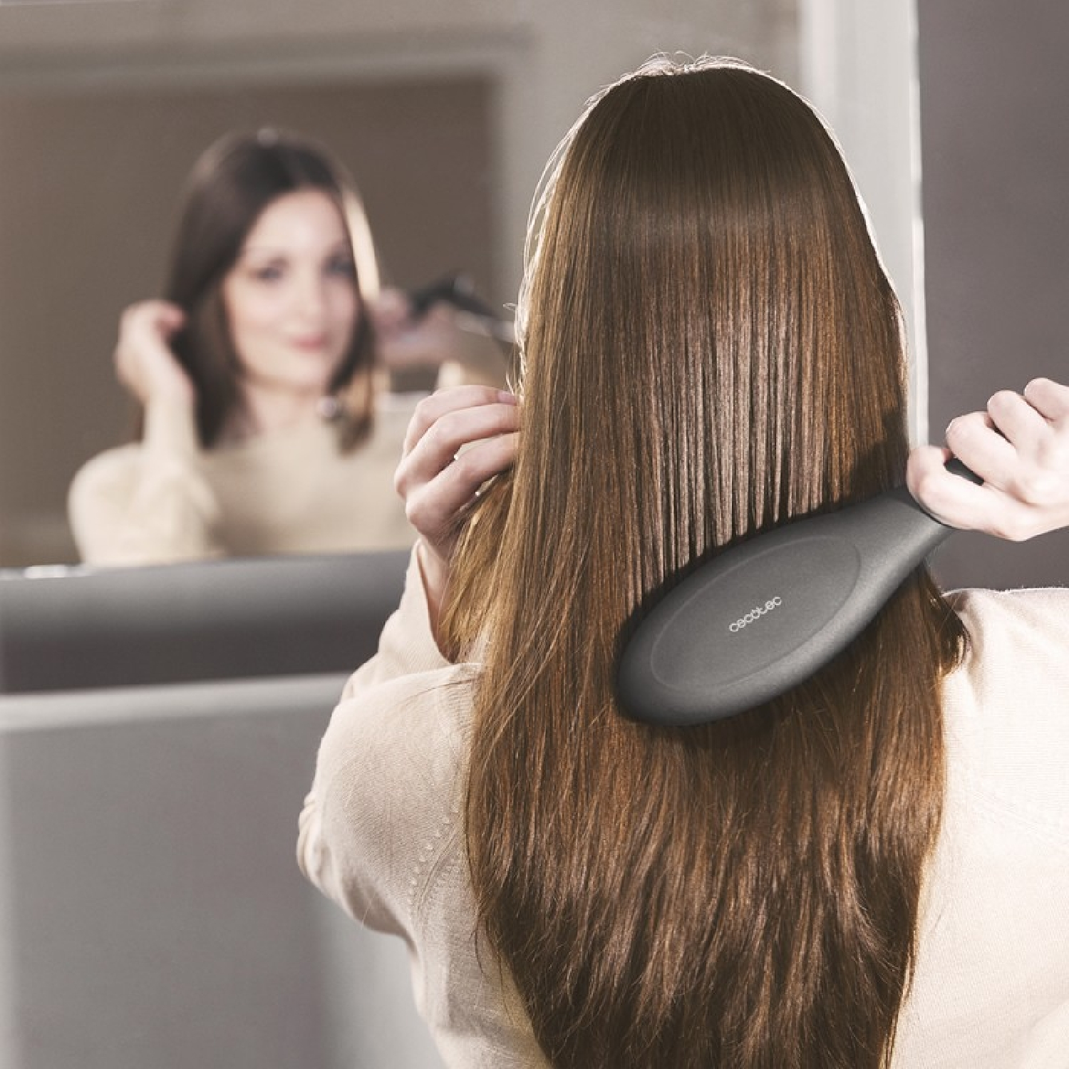 Vrouw die haar haar borstelt, in een spiegel kijkt. Een zwarte borstel in haar rechterhand.