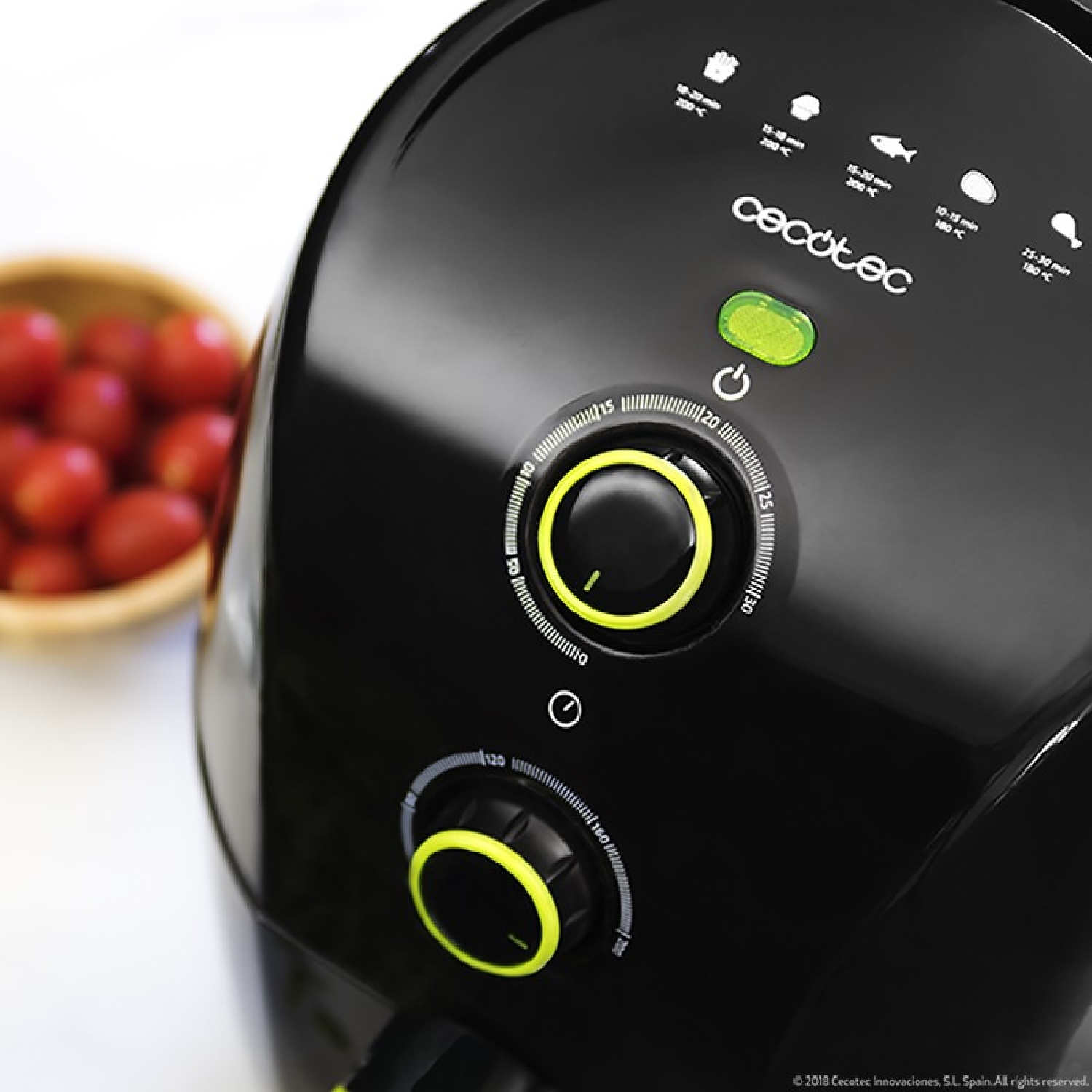 Freidora de aire negra con panel de control, temporizador y diales de temperatura. Tomates en cuenco madera.