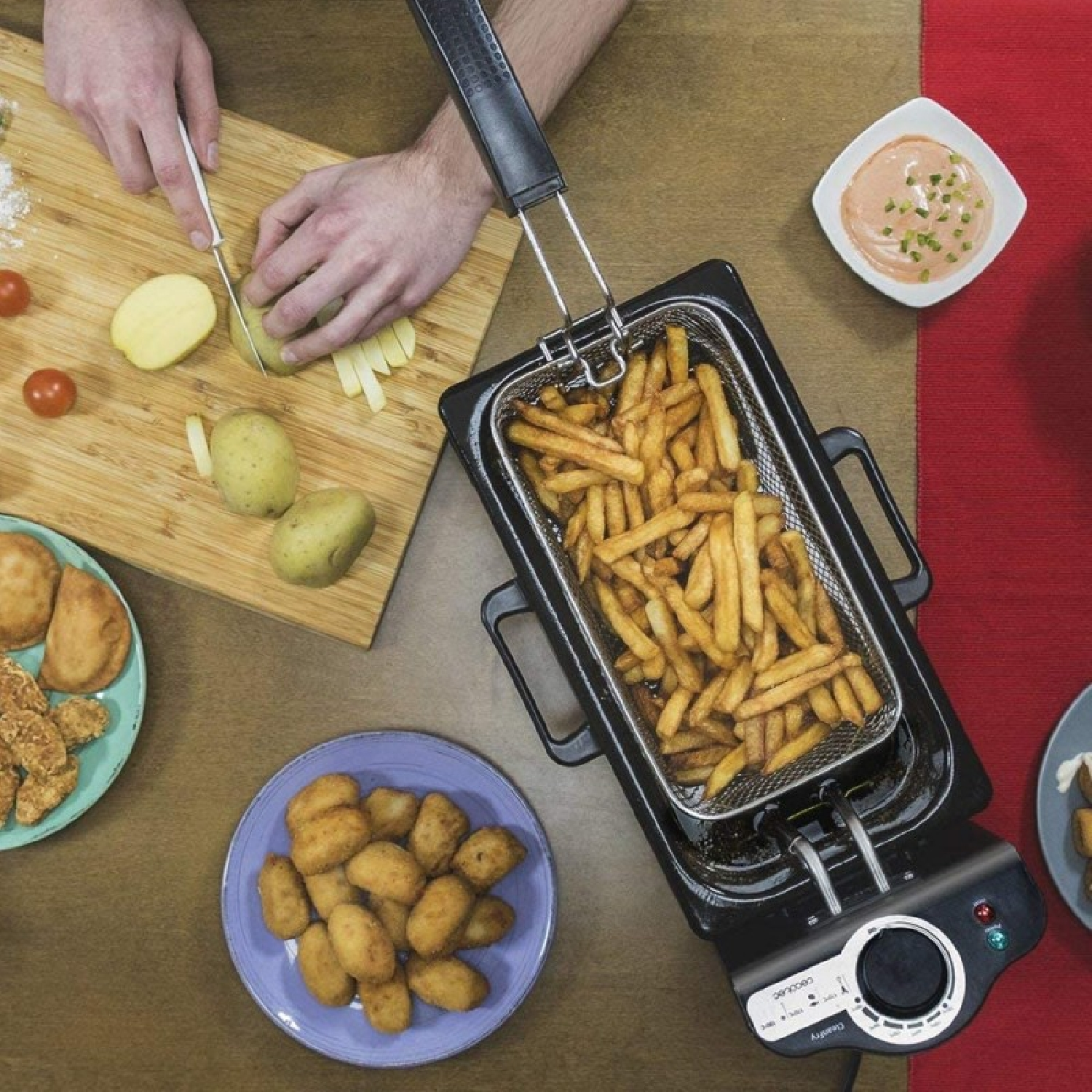 Persona cortando patatas en una tabla de madera, friendo patatas fritas en una freidora, con salsa.
