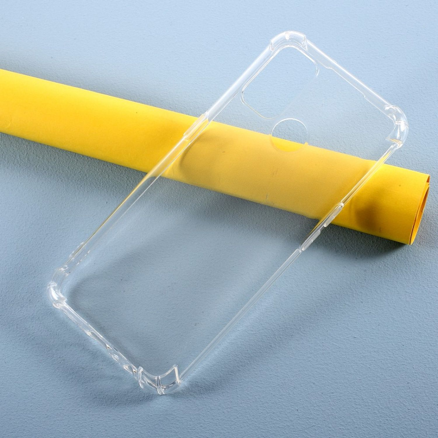 Eine transparente Handyhülle auf einer blauen Oberfläche mit einer gelben Papierrolle im Hintergrund.