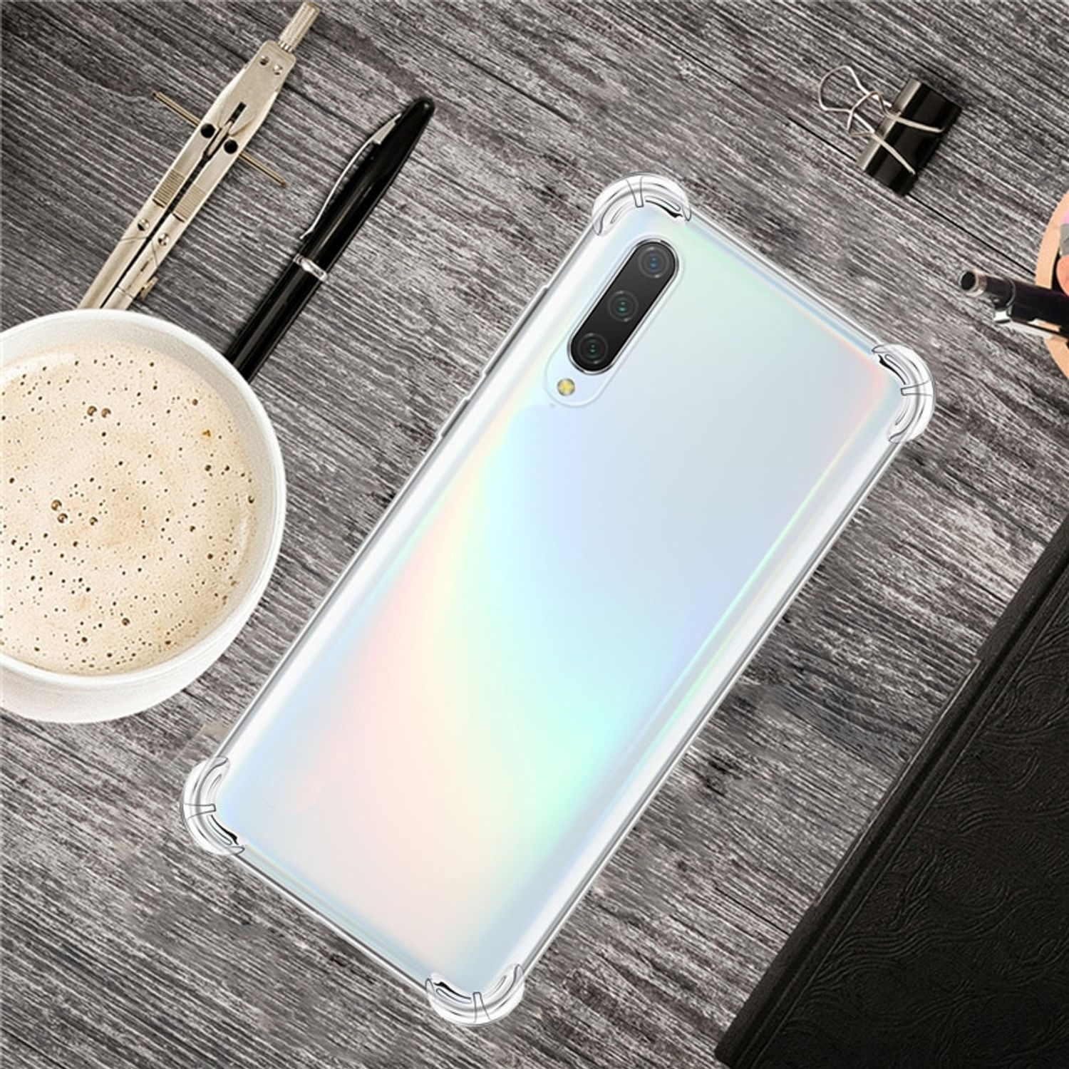 Ein Telefon mit durchsichtiger Hülle auf einem Holztisch mit Kaffee, Stift und anderen Gegenständen.