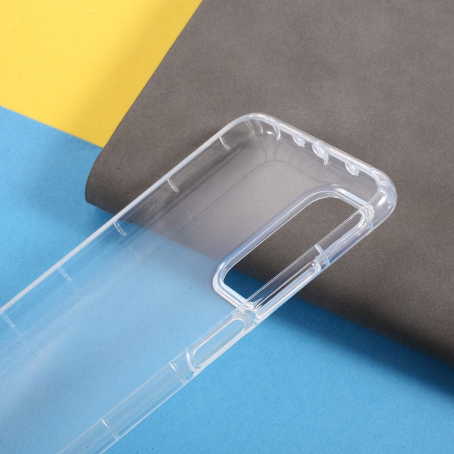 Transparente Handyhülle auf blauem, gelbem und grauem Hintergrund. Die Hülle ist leer.