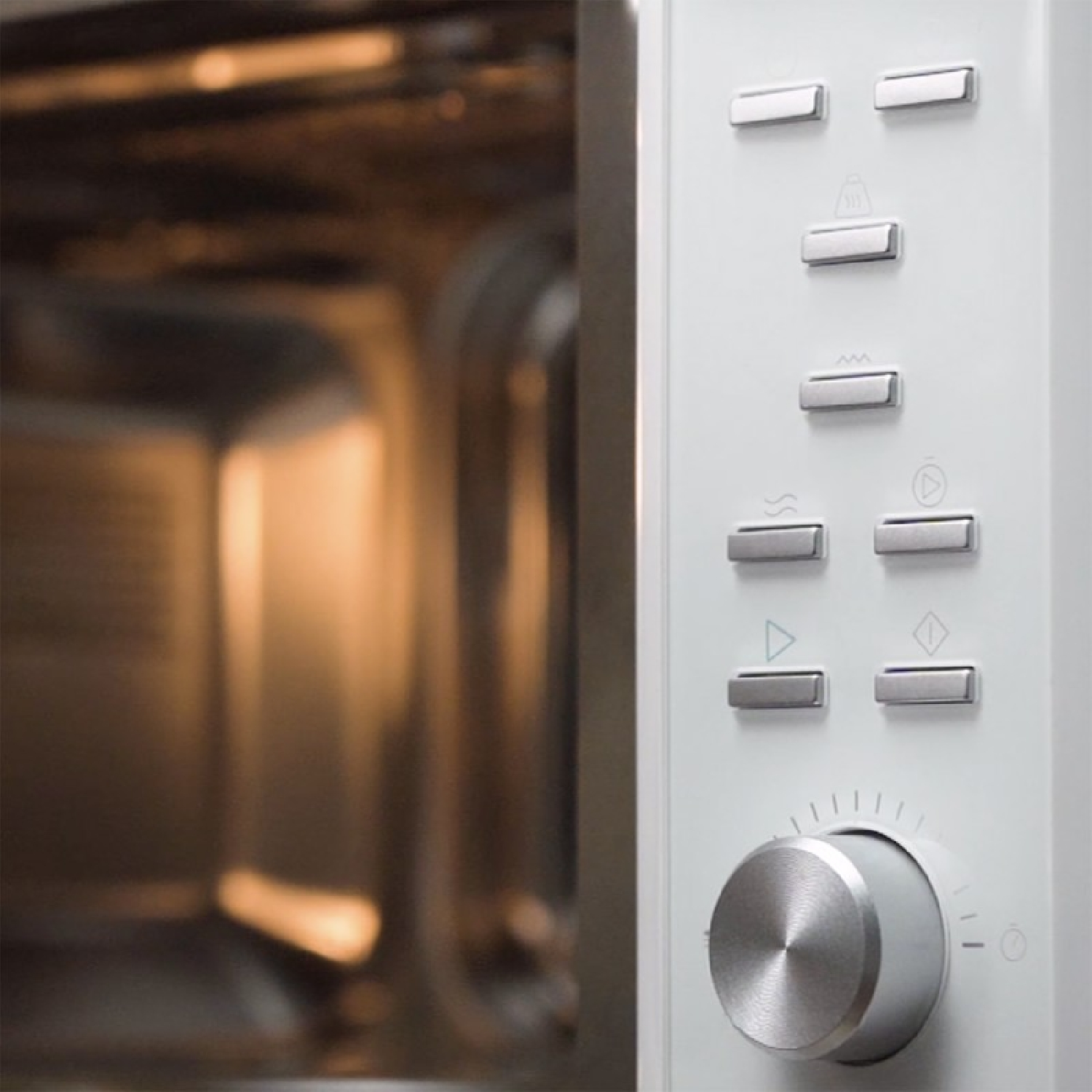 Wnętrze kuchenki mikrofalowej z otwartymi drzwiami. Biały panel sterowania po prawej stronie. Widoczne przyciski i pokrętło.