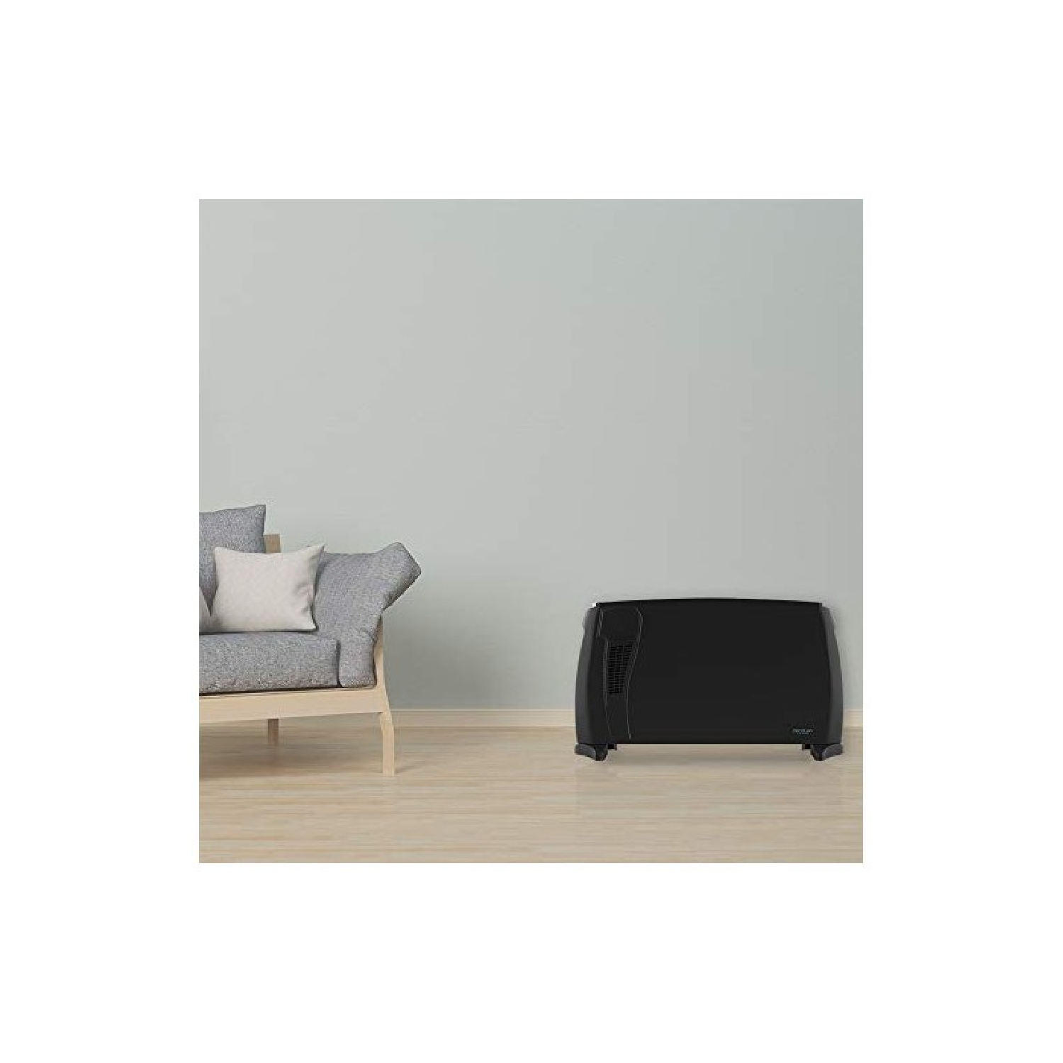 Zwarte elektrische kachel naast een grijze fauteuil op lichte houten vloer.