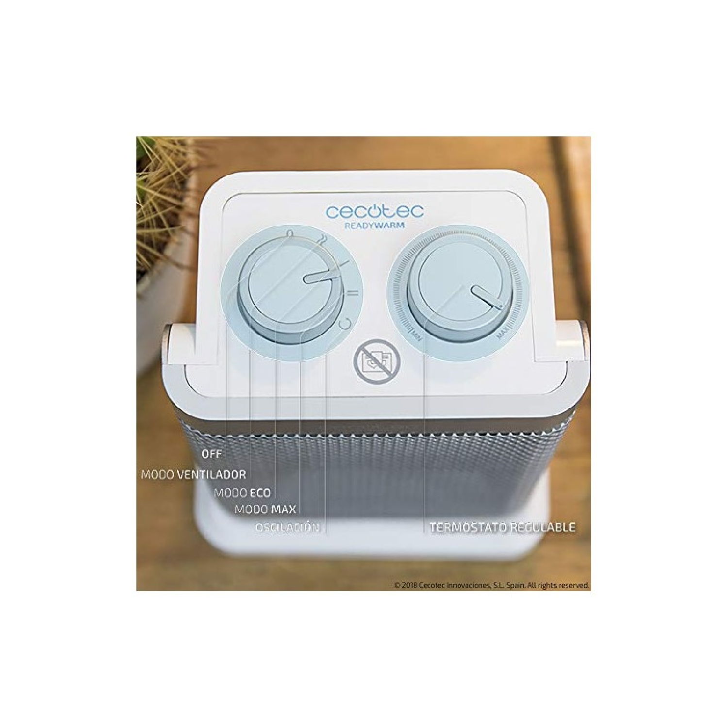 Biało-szary grzejnik elektryczny z dwoma niebieskimi pokrętłami na górze. Tekst na grzejniku jest po hiszpańsku.