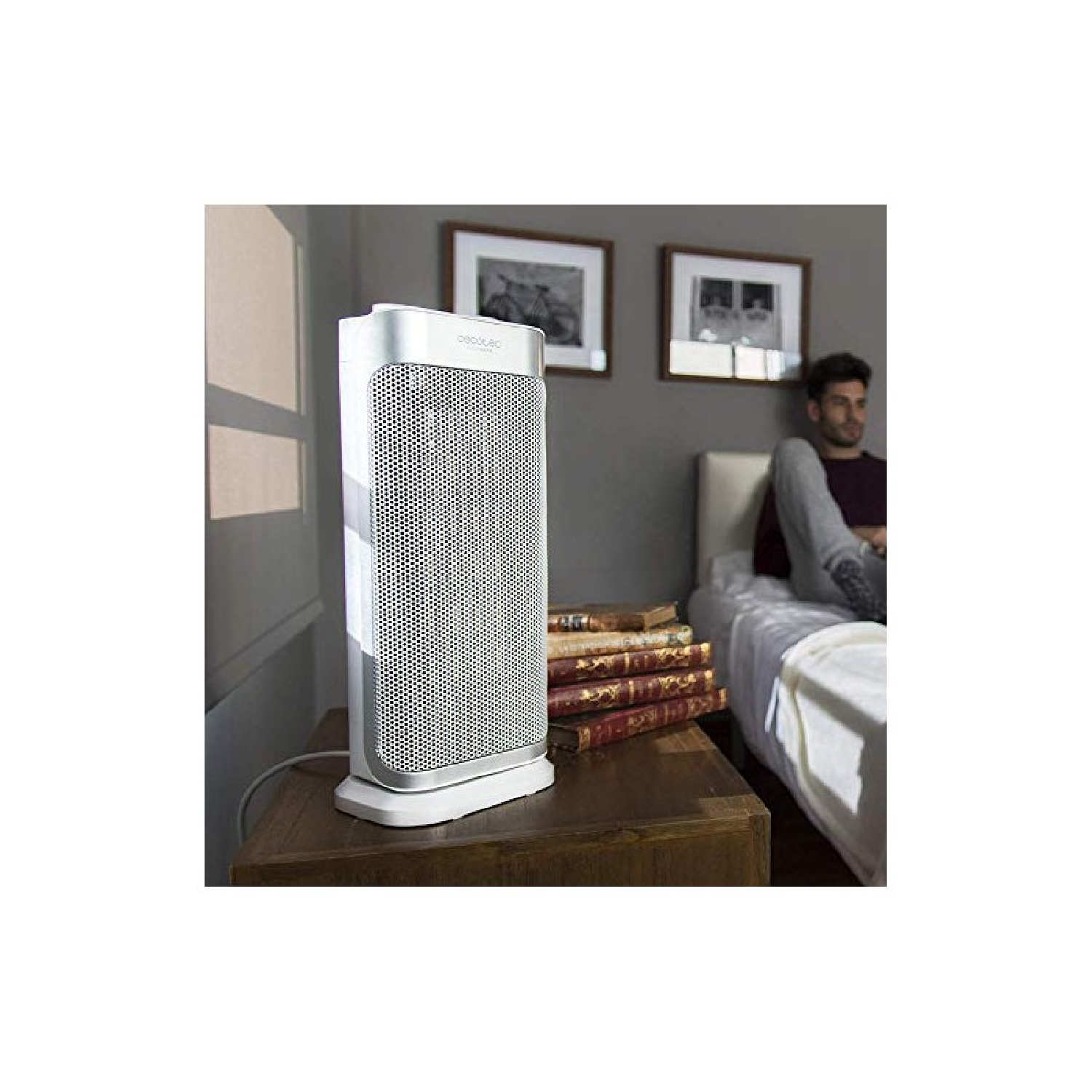 Biało-srebrny grzejnik. Mężczyzna siedzi na łóżku w tle.