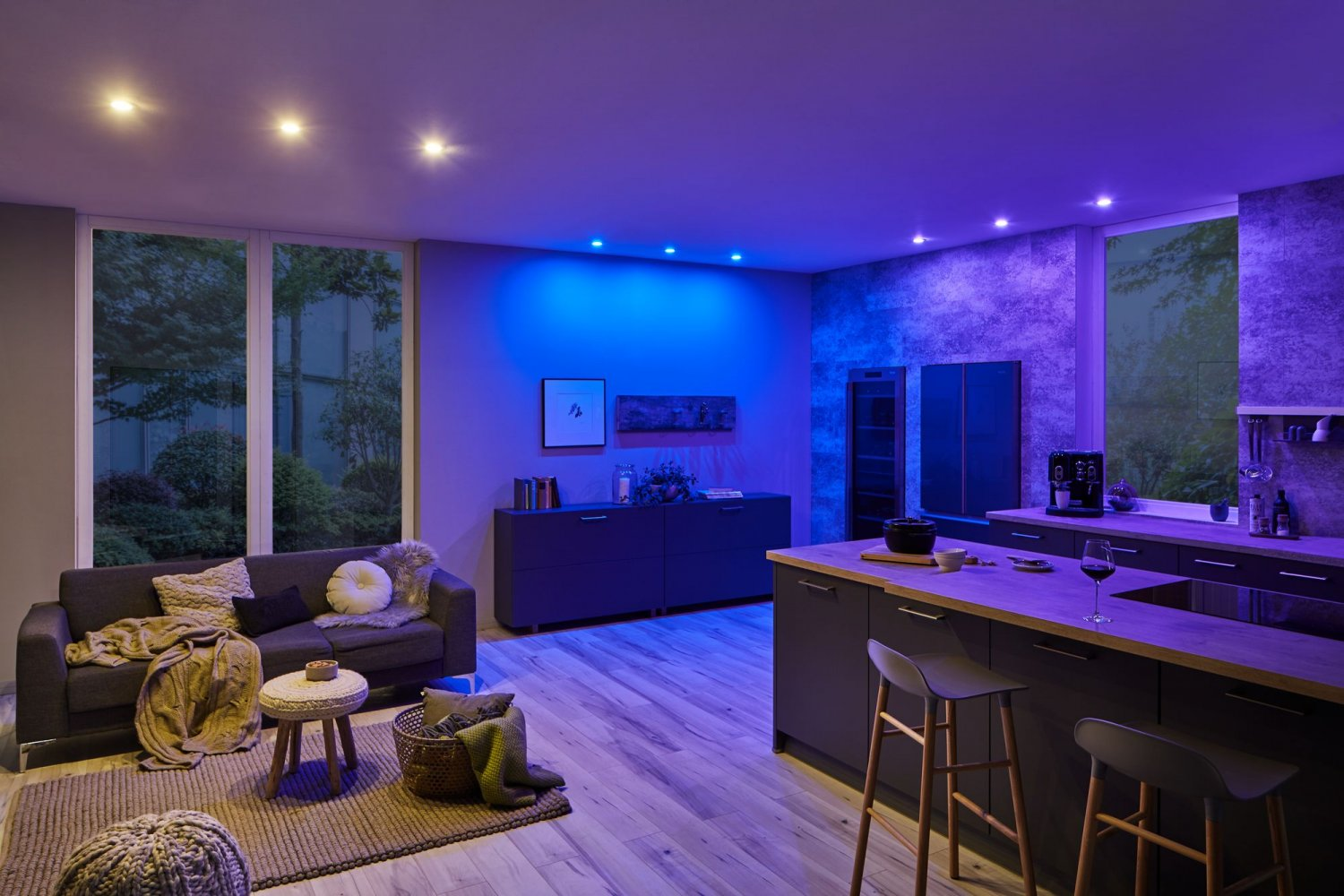 Ein modernes Wohnzimmer, beleuchtet mit blauem Licht, mit Sofa und Küche.