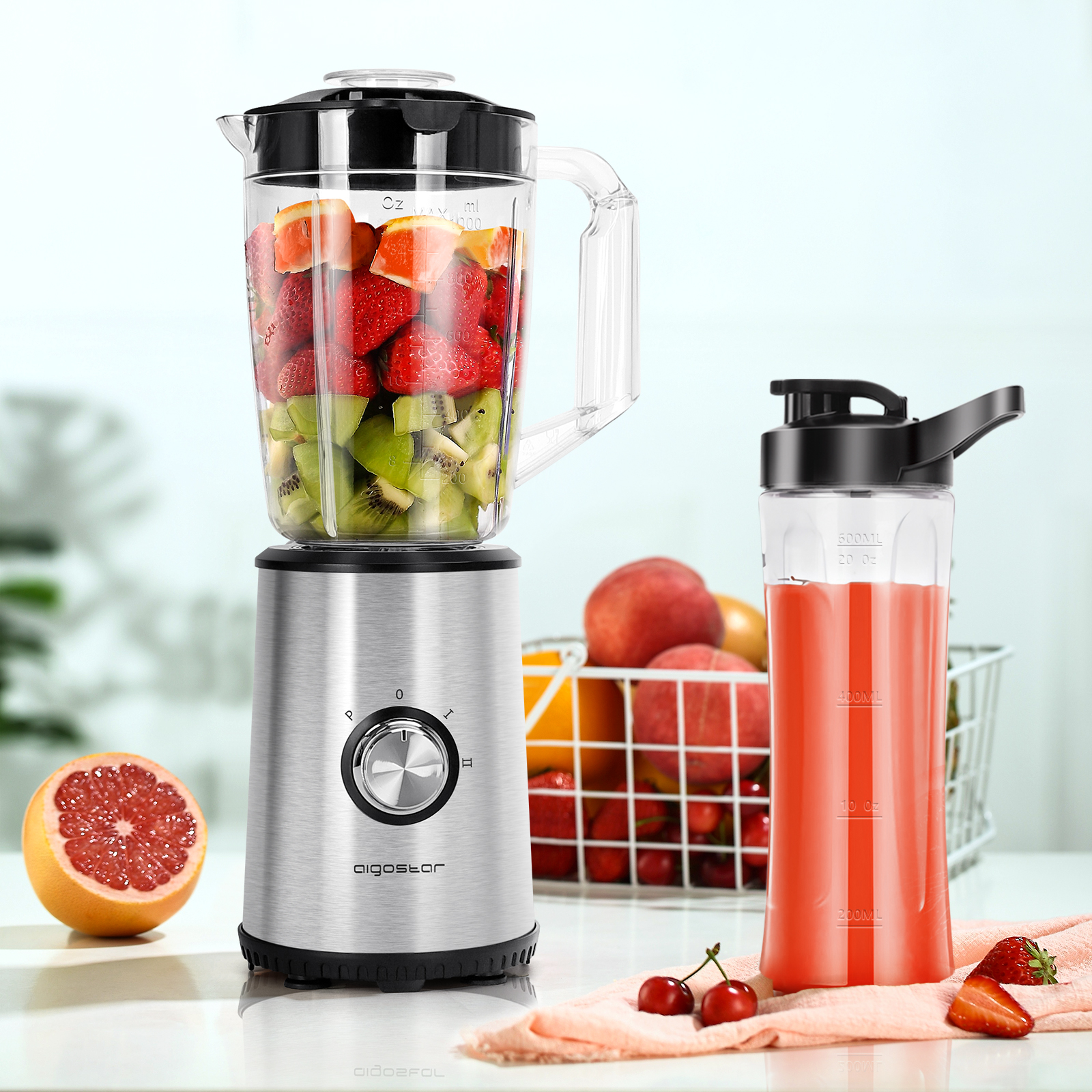 Mixer mit Früchten und einer Saftflasche. Eine halbe Grapefruit und Kirschen sind vorne.