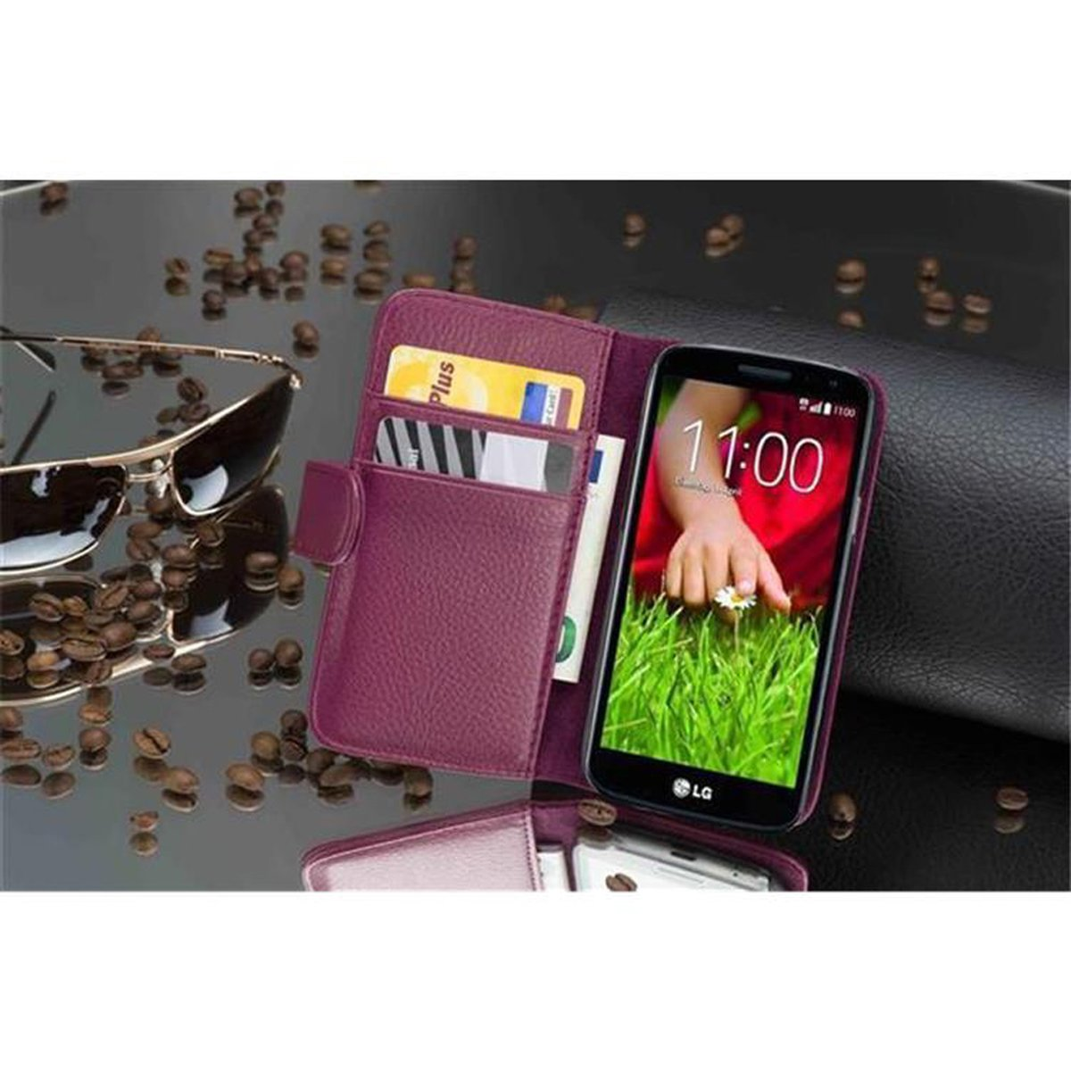 Un telefono in una custodia viola con carte di credito e denaro. Occhiali da sole e chicchi di caffè sparsi.