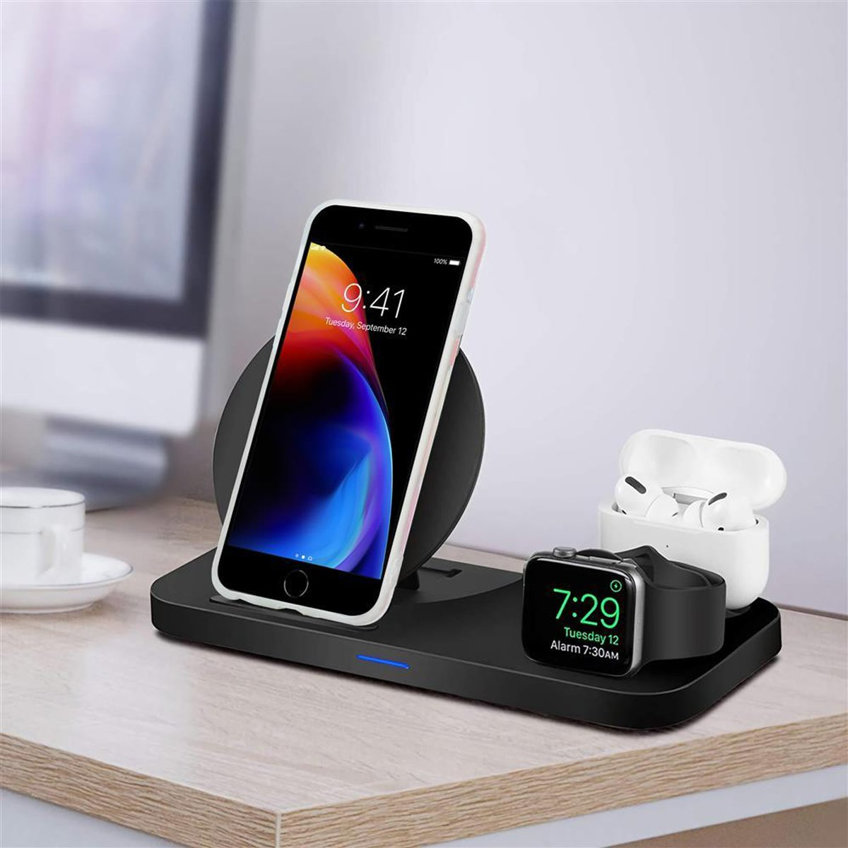 Caricatore wireless con telefono, auricolari e smartwatch su una scrivania.