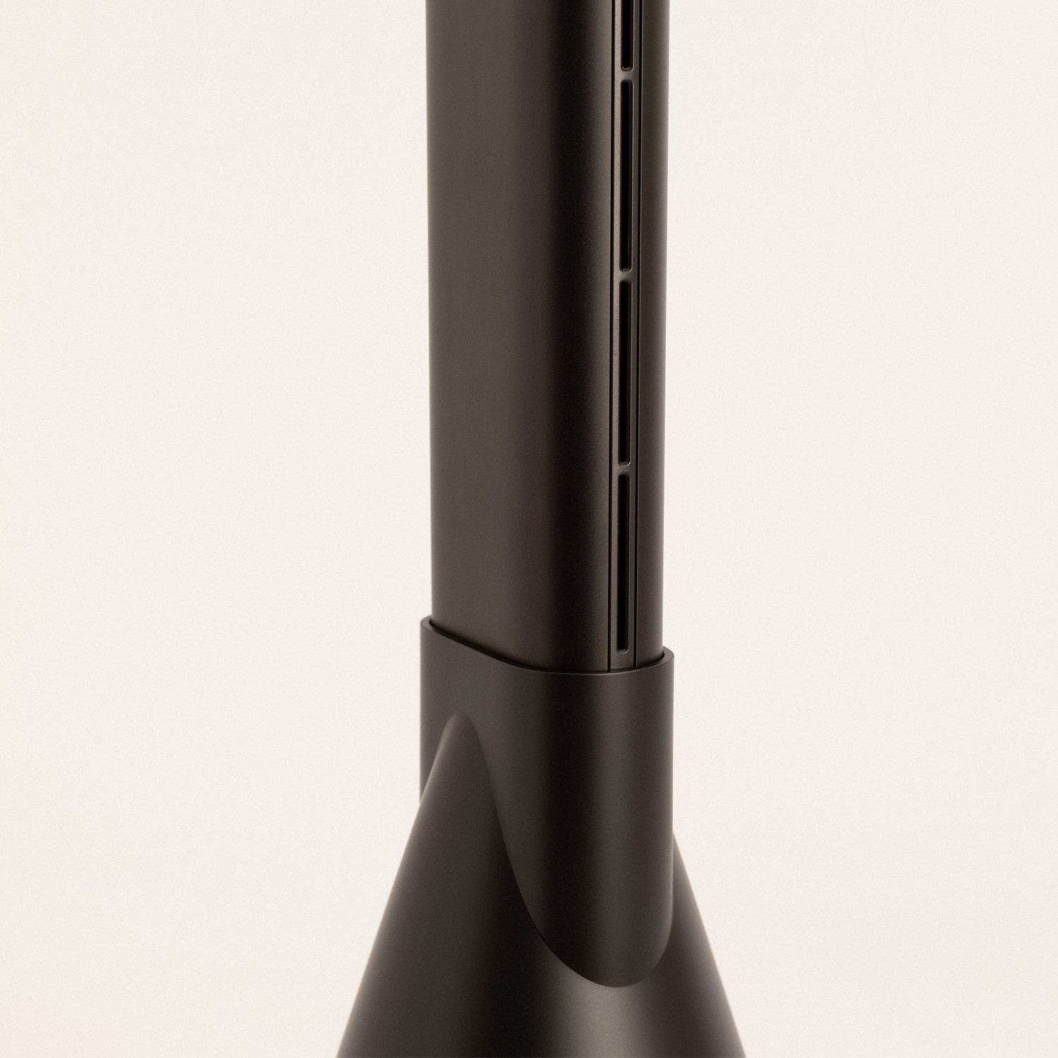 Soporte de dispositivo negro, alto y estrecho, con ranuras verticales. Se apoya en una base sólida.